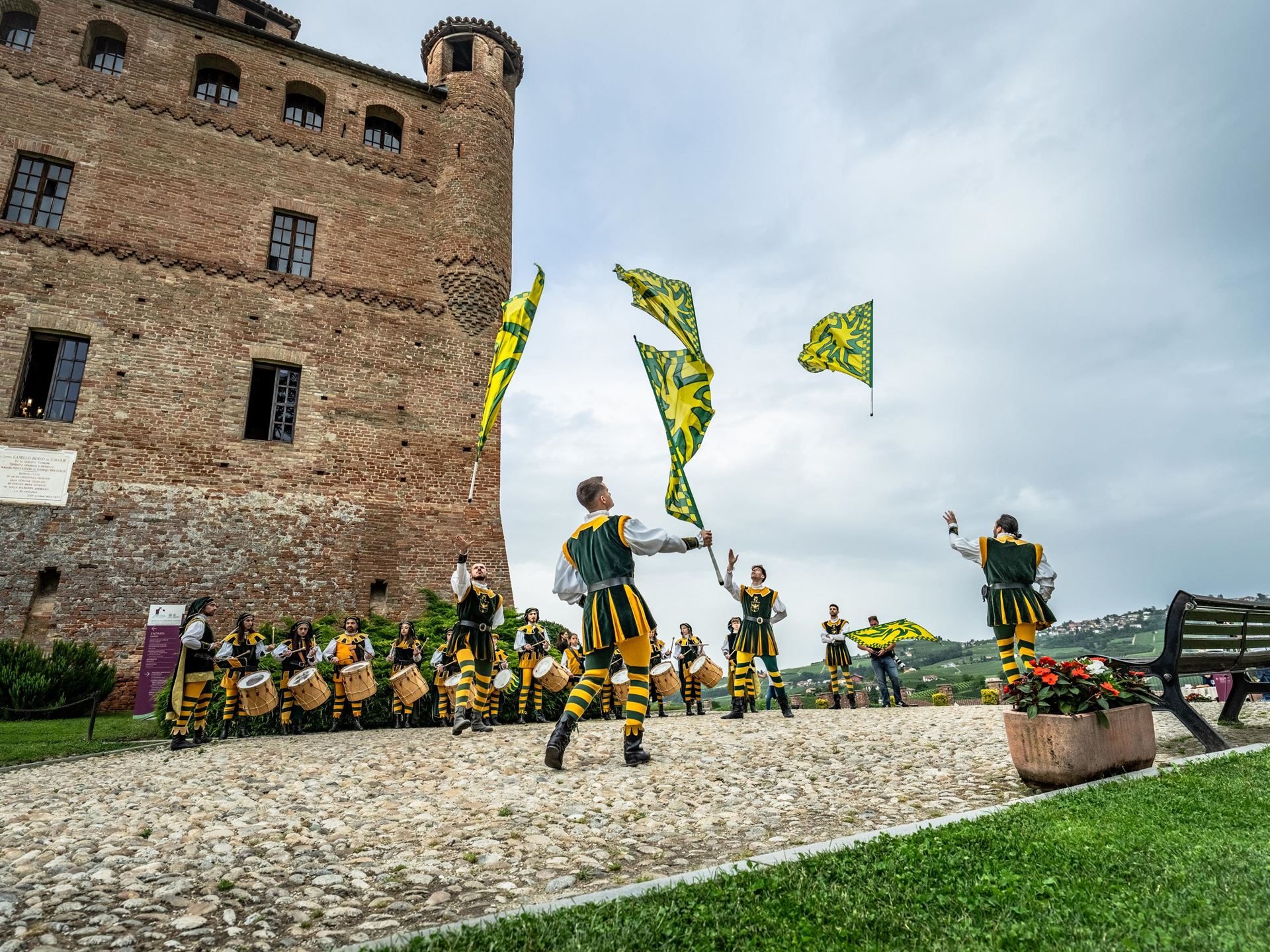 Performers in medieval costumes with drums and flags in front of a brick castle during the esperienza giro dinner