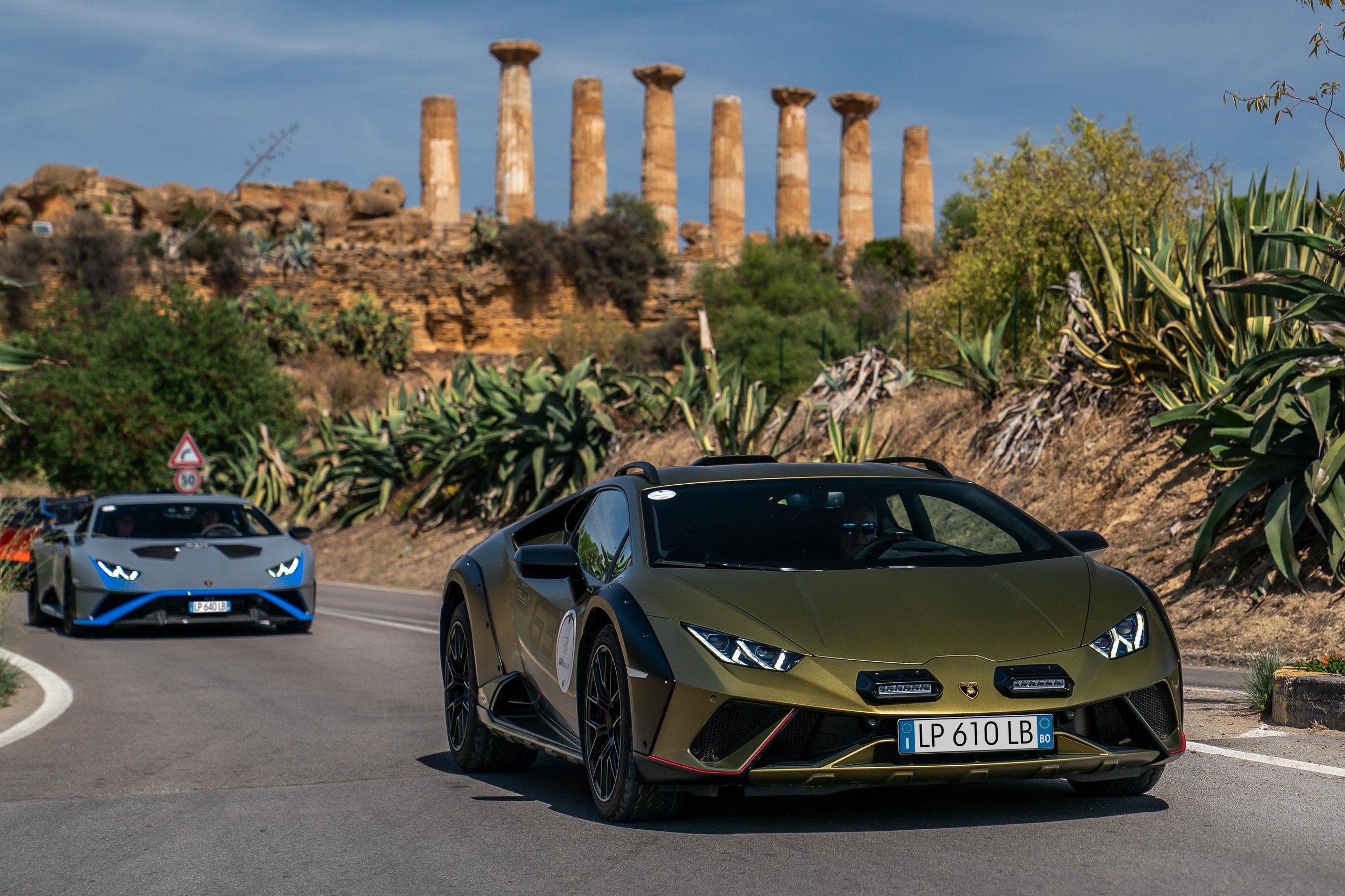 Esperienza Giro Sicilia: How Lamborghini Turned 750 Km Of Ancient Roads Into Its Most Personal Anniversary Statement 5 Olive green lamborghini huracán sterrato driving past ancient greek temple ruins followed by a grey huracán tecnica