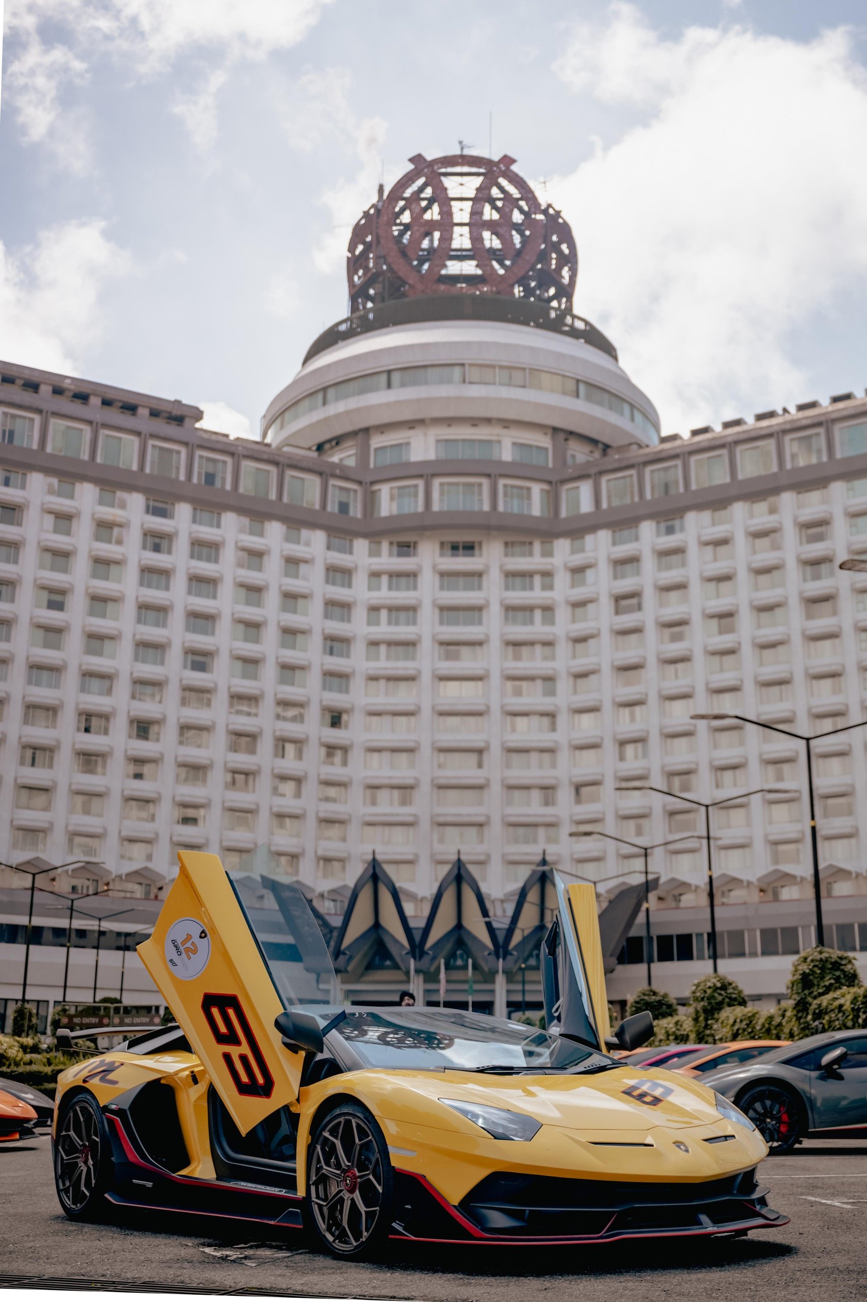 Lamborghini'S First Southeast Asia Esperienza Giro Turned Malaysia Into A Rolling 60Th Birthday Party 9 Yellow lamborghini aventador svj with scissor doors open parked in front of an ornate hotel building