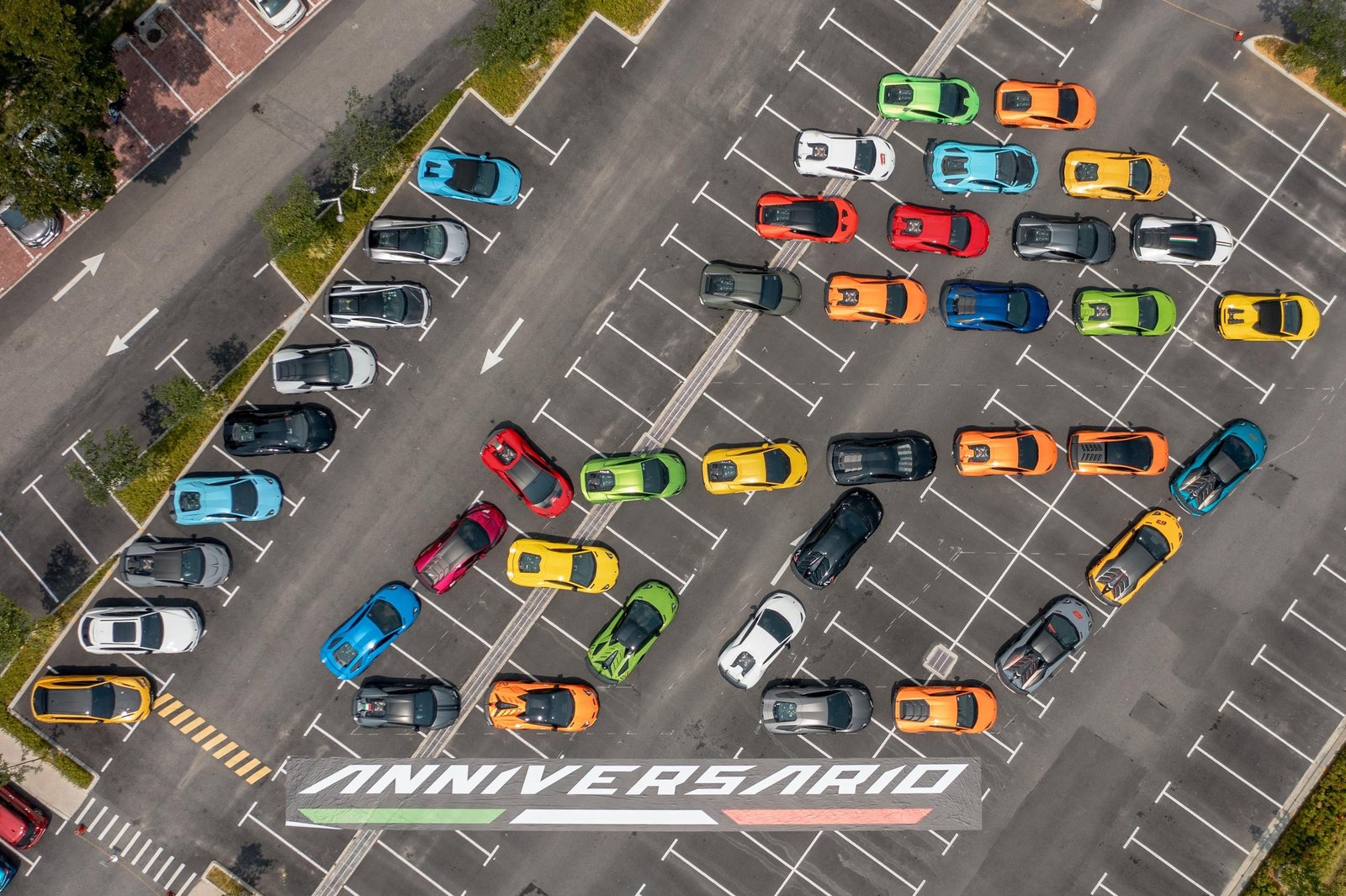 Aerial view of colorful Lamborghini cars arranged to spell 60 ANNIVERSARIO in a parking lot