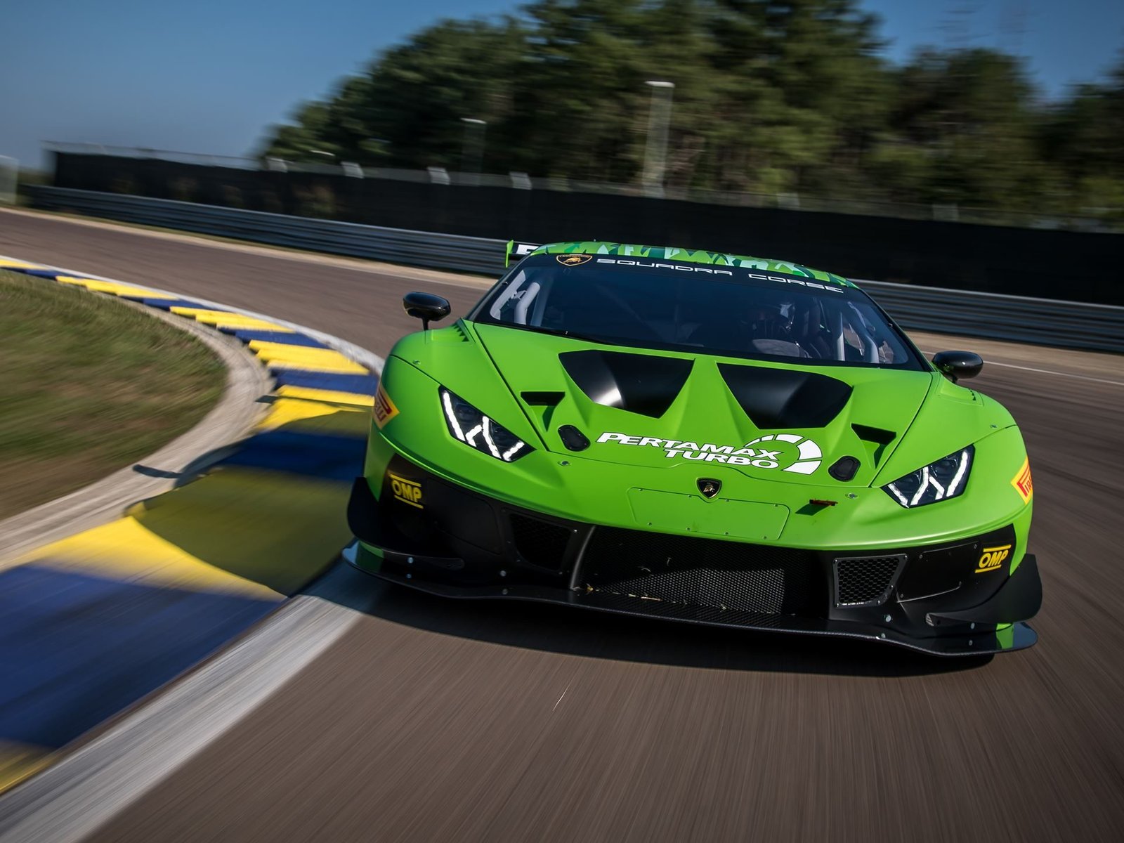 Lamborghini Huracán GT3 EVO racing on circuit with visible carbon fiber aero elements, large front splitter, and racing slicks
