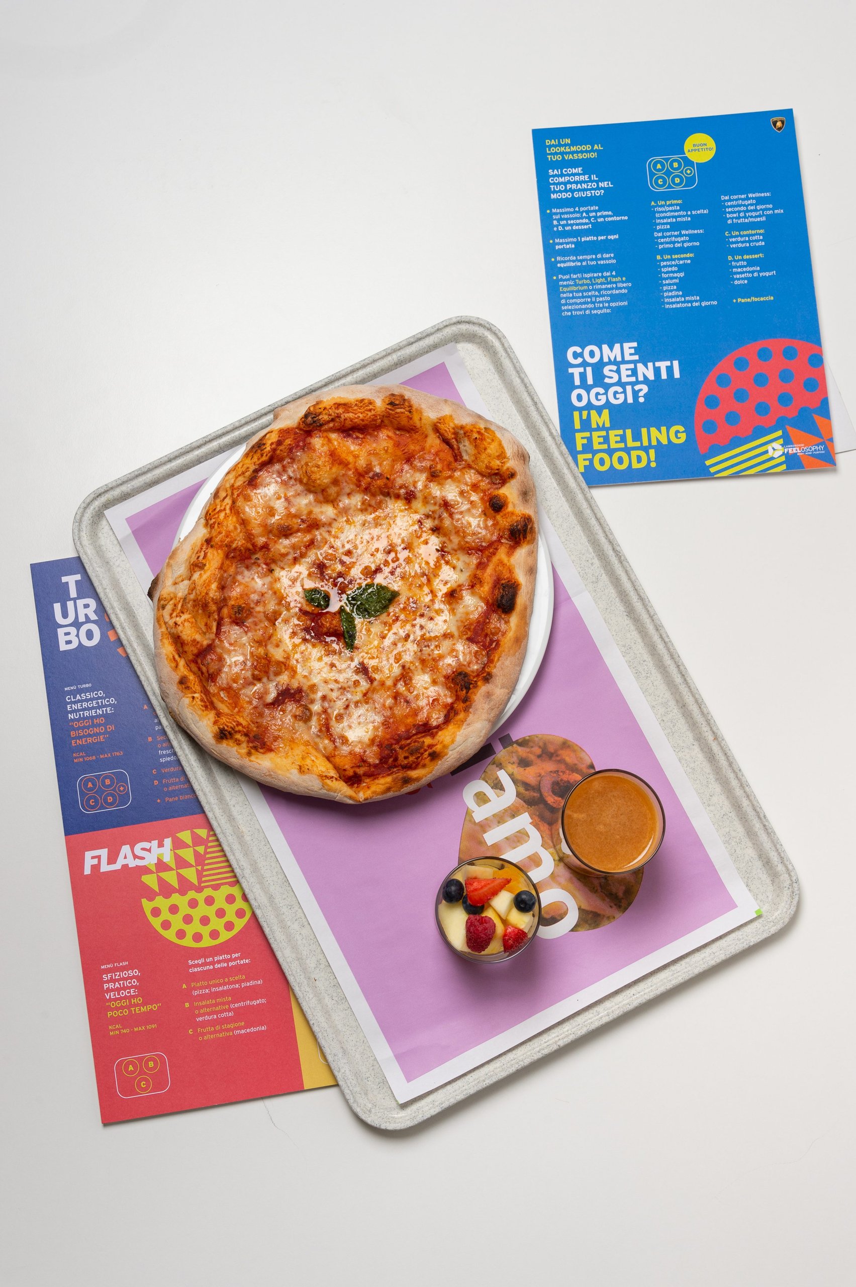 Overhead view of a Lamborghini employee meal tray with FEELOSOPHY nutrition cards and healthy food options