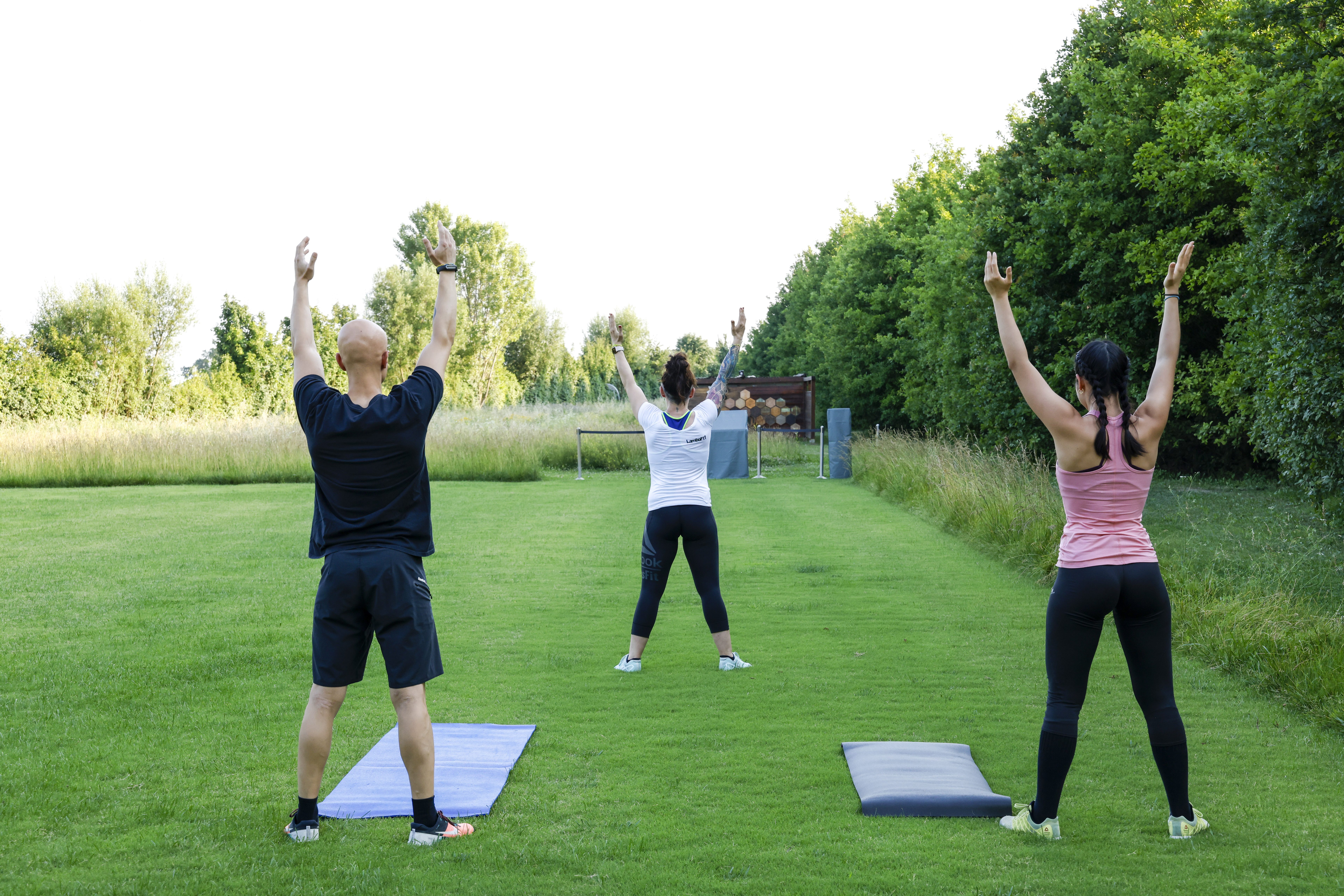 Lamborghini'S Feelosophy Program Bets That Better-Supported Employees Build Better Supercars 5 Lamborghini employees performing outdoor exercises with arms raised on yoga mats as part of feelosophy body pillar