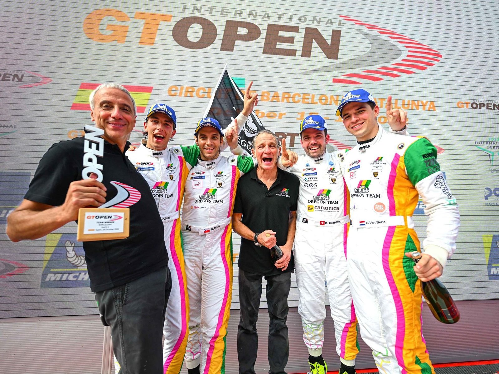 Oregon Team drivers and crew celebrate on the International GT Open podium with trophies and champagne after clinching Lamborghini's fifth championship title