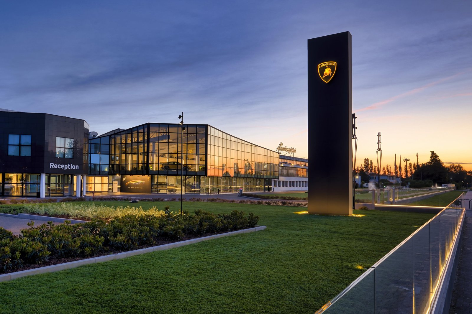Lamborghini factory and reception building illuminated at sunset with prominent Lamborghini sign