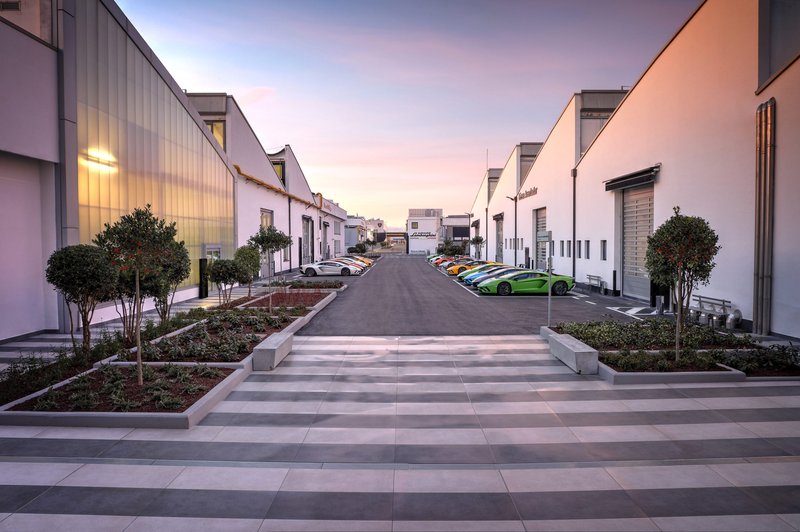 Colorful Lamborghini supercars lined up along the pathway at the Sant'Agata Bolognese factory complex at dusk