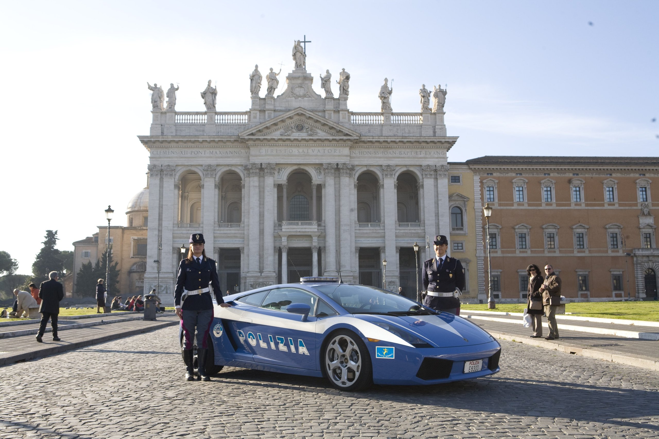 Blue and white Lamborghini Gallardo LP 560-4 Polizia car with two Italian police officers in front of a historic building