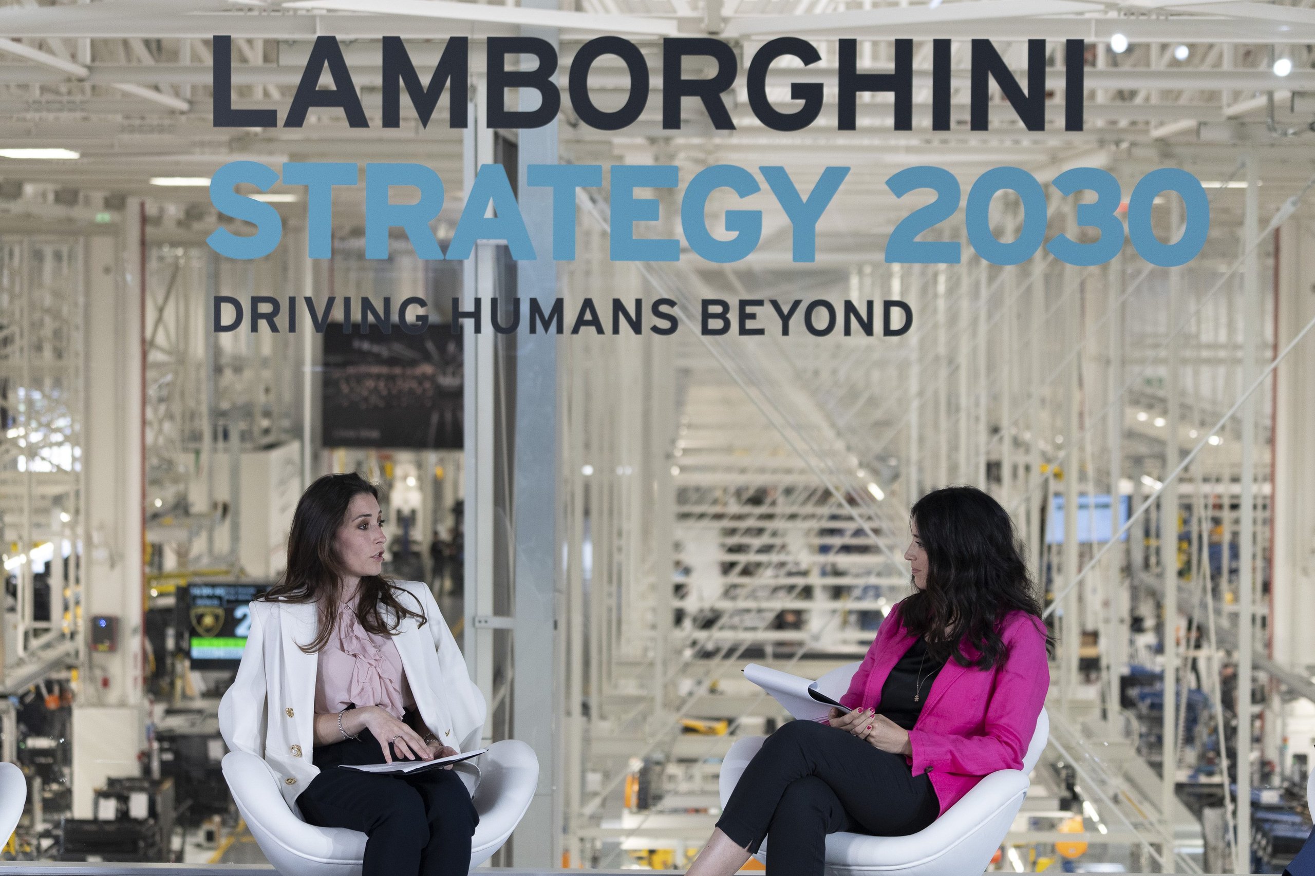 Lamborghini'S Gender Equality Certification Puts Sant'Agata Ahead Of Most Rivals, But What Does It Actually Mean? 3 Two women seated at a lamborghini corporate event with a screen displaying lamborghini strategy 2030 driving humans beyond