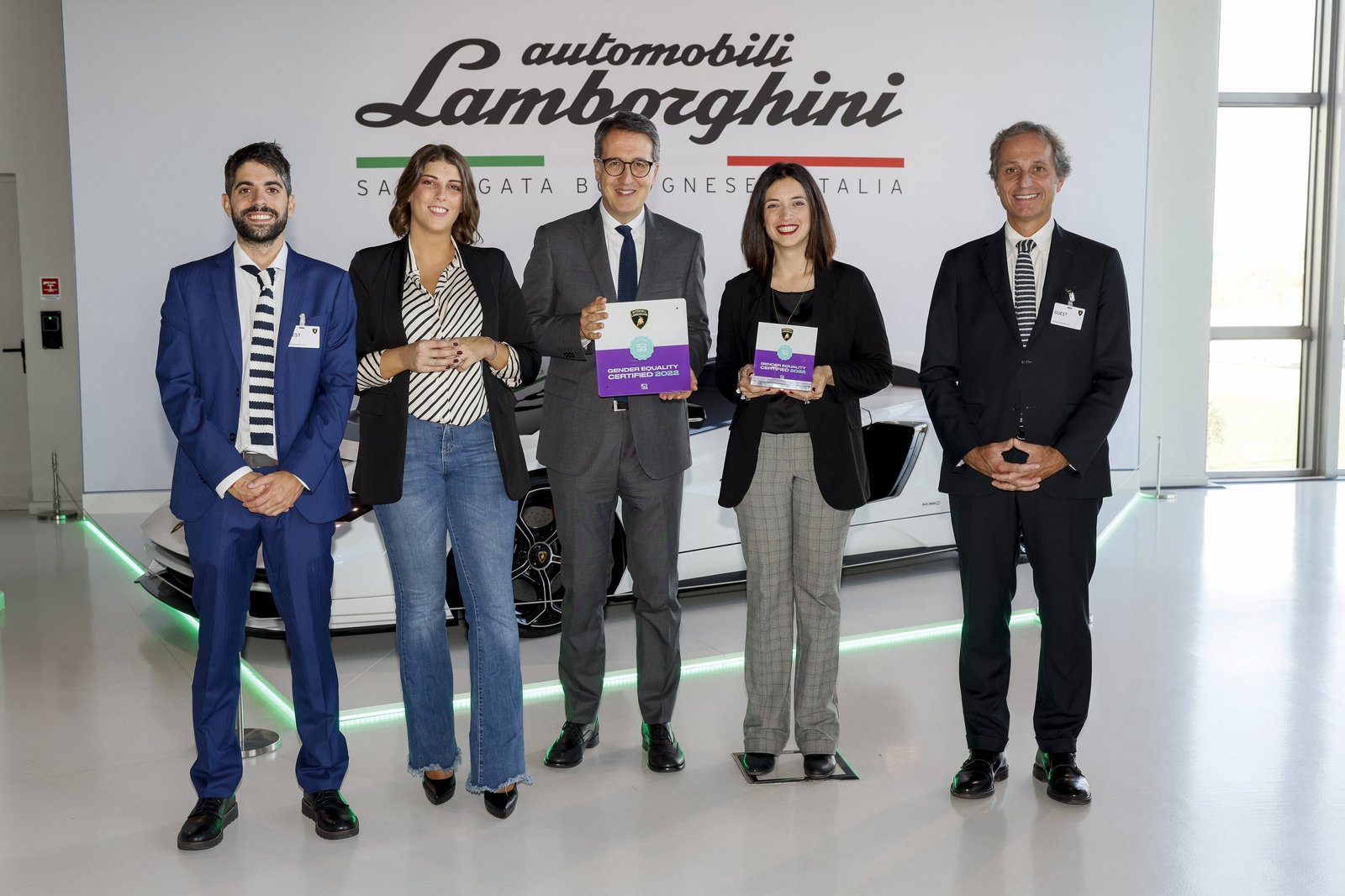 Lamborghini executives and employees holding UNI/PdR 125:2022 gender equality certificates in front of a white Revuelto
