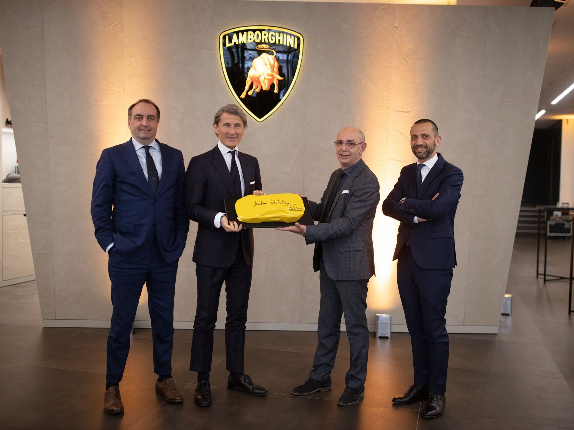 Lamborghini Geneva Celebrates 20 Years With A Showroom Built For The Brand'S Next Chapter 11 Stephan winkelmann and executives holding a yellow plaque in front of the lamborghini logo at the geneva showroom inauguration