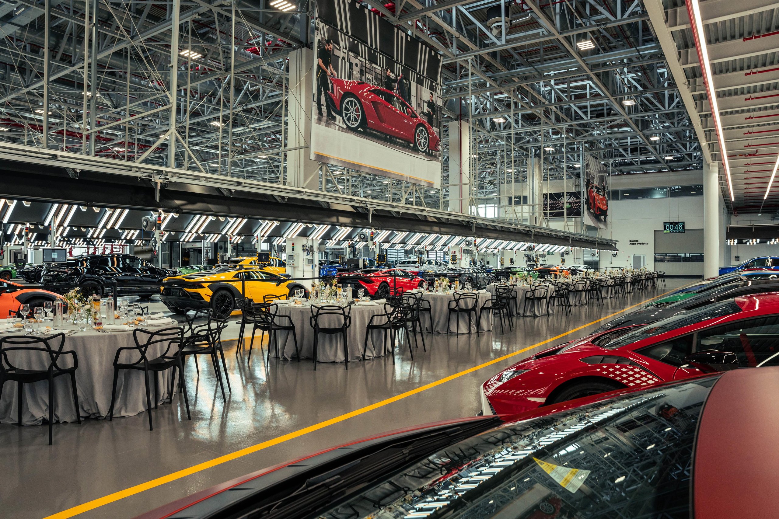 How Lamborghini Turned Italy'S Roads Into A Rolling Museum For Its 60Th Anniversary 5 Wide shot of the giro polo storico gala dinner inside lamborghini's factory with classic cars, dining tables, and heritage banners hanging from the ceiling