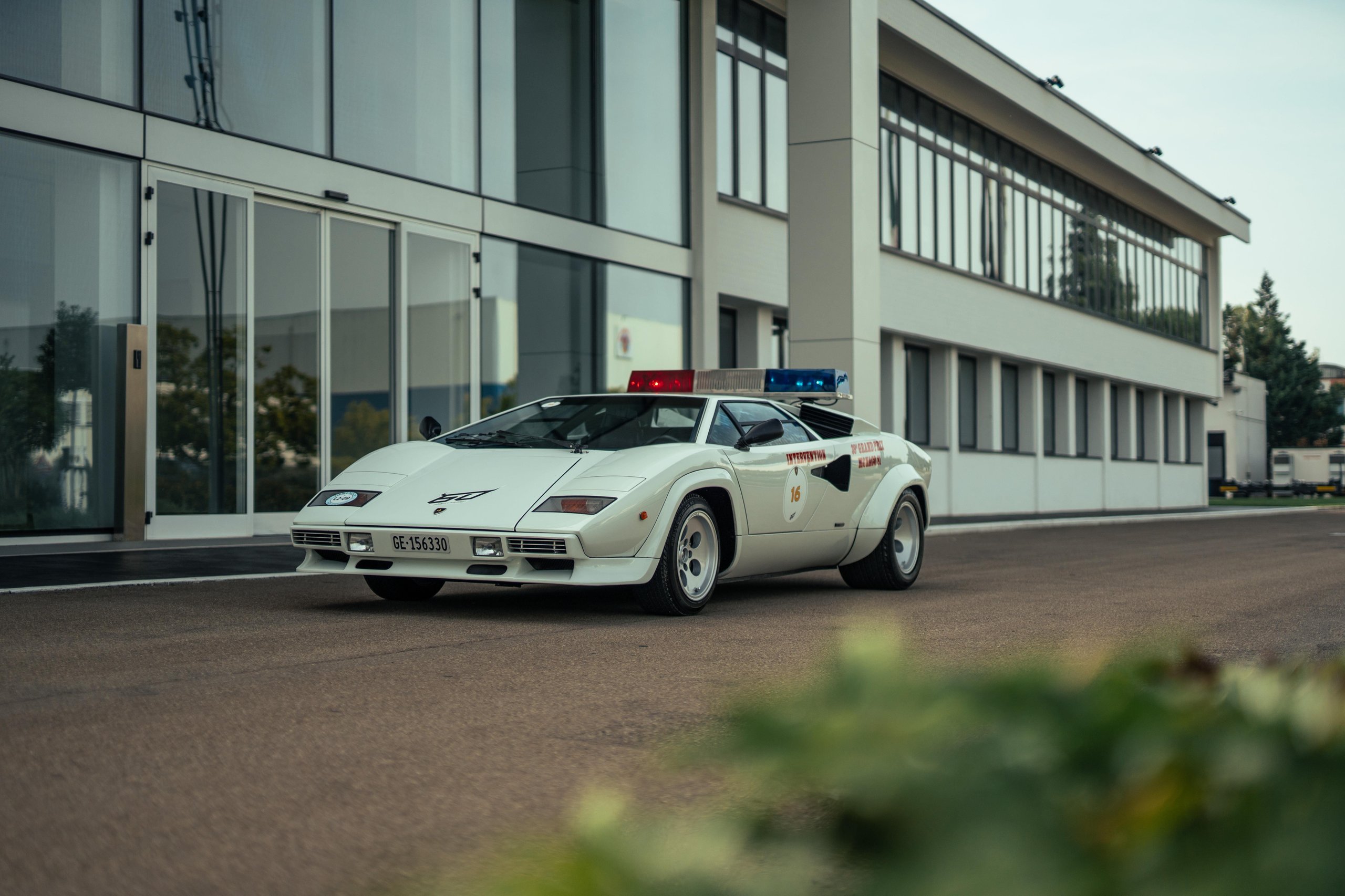 How Lamborghini Turned Italy'S Roads Into A Rolling Museum For Its 60Th Anniversary 9 White lamborghini countach lp 400 s with police light bar on its roof, the 1981 monaco f1 pace car, parked in front of a modern building