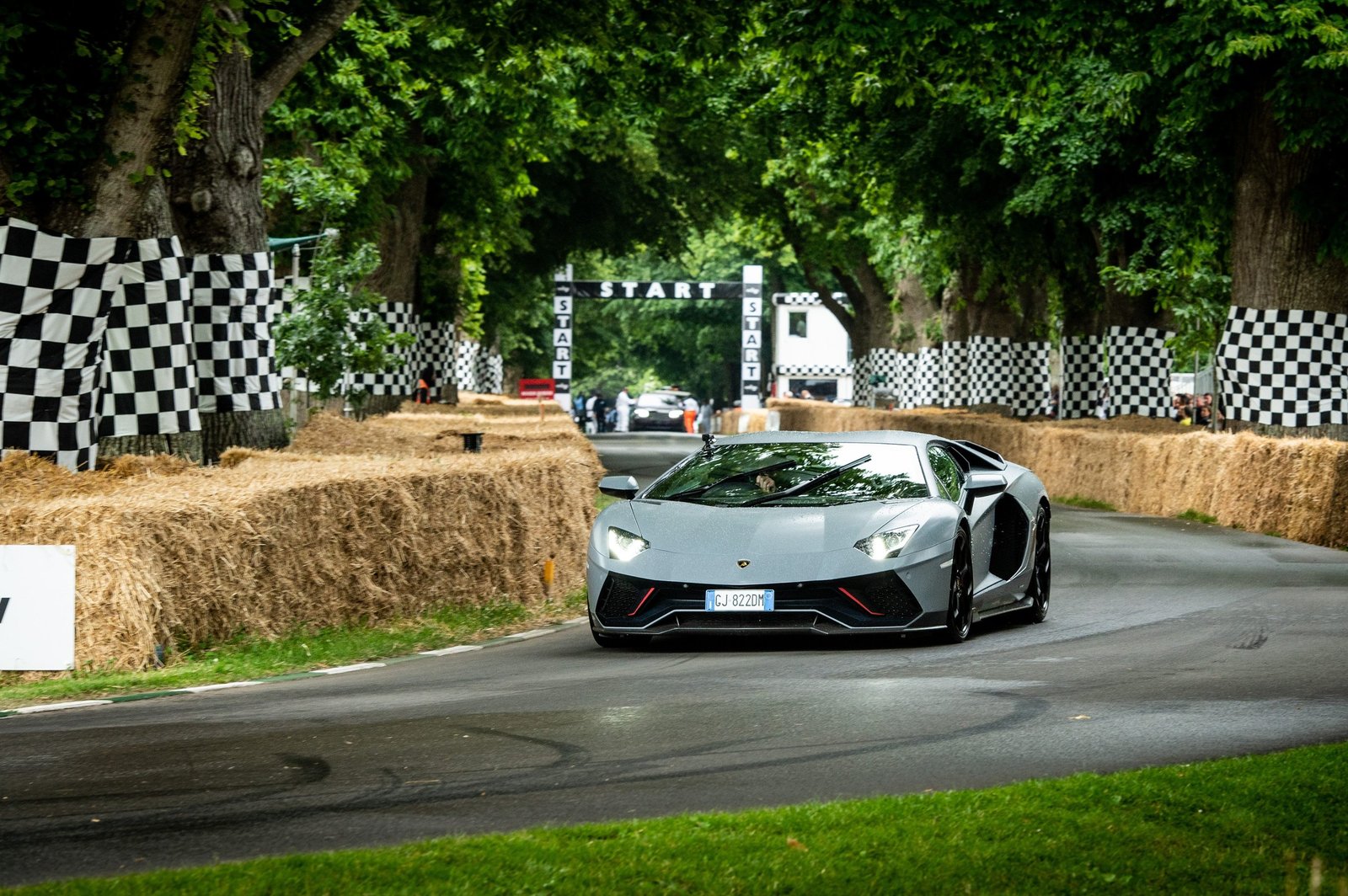 Grey Lamborghini Aventador accelerating past the start banner at the Goodwood Festival of Speed hill climb
