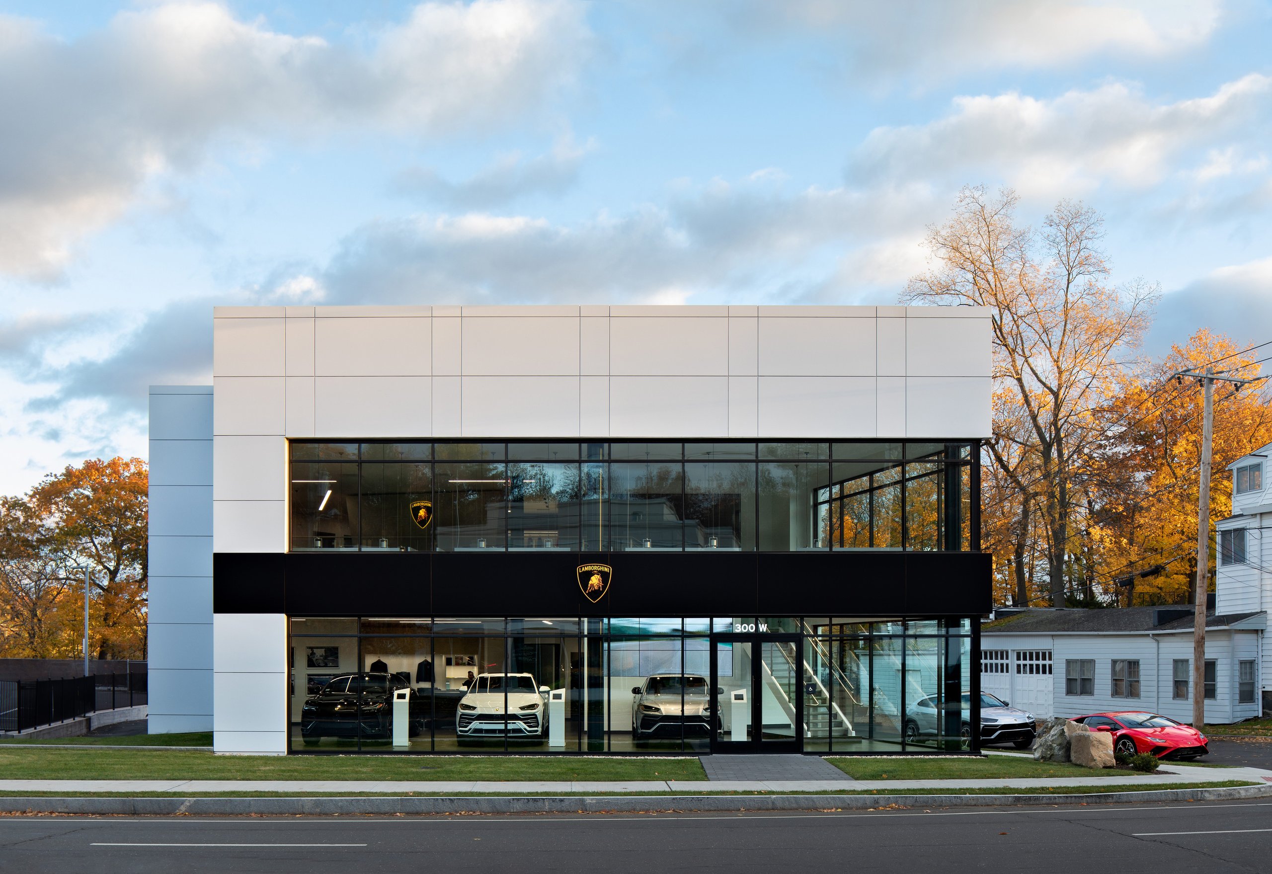 Lamborghini Greenwich Opens With A Proper Ad Personam Studio, And That Matters More Than The Ribbon Cutting 7 Daytime exterior of the lamborghini greenwich showroom with urus suvs visible inside and a red huracán evo parked outside