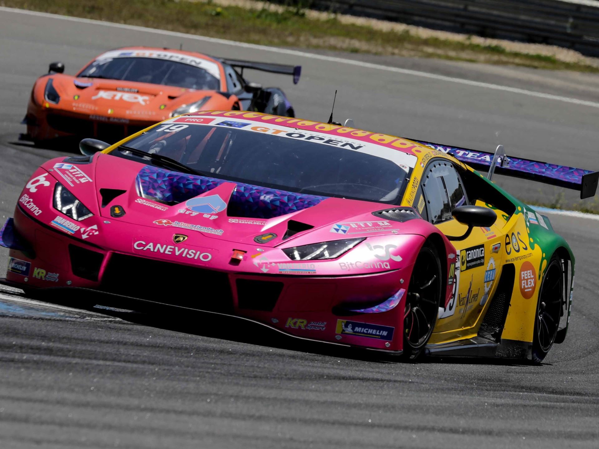 Oregon Team'S Clean Sweep At Estoril And Bortolotti'S Dtm Lead Signal The Huracán Gt3 Evo Still Owns Gt Racing 7 Pink and yellow oregon team lamborghini huracán gt3 evo number 19 cornering at estoril with an orange competitor car visible behind