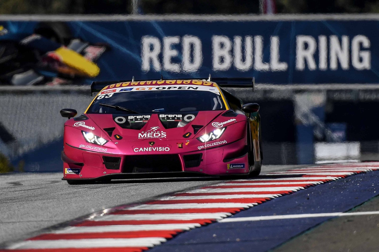 Oregon Team's pink and yellow Lamborghini Huracán GT3 Evo racing through a corner at the Red Bull Ring