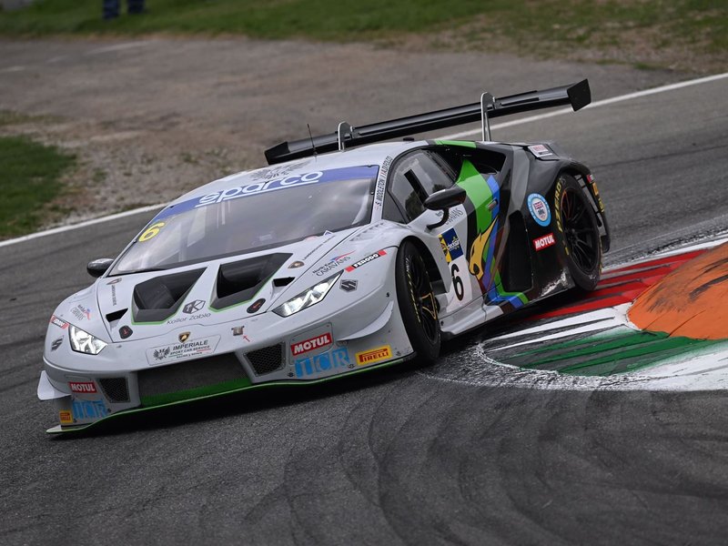 White Lamborghini Huracán GT3 EVO race car with green and black accents cornering hard on track