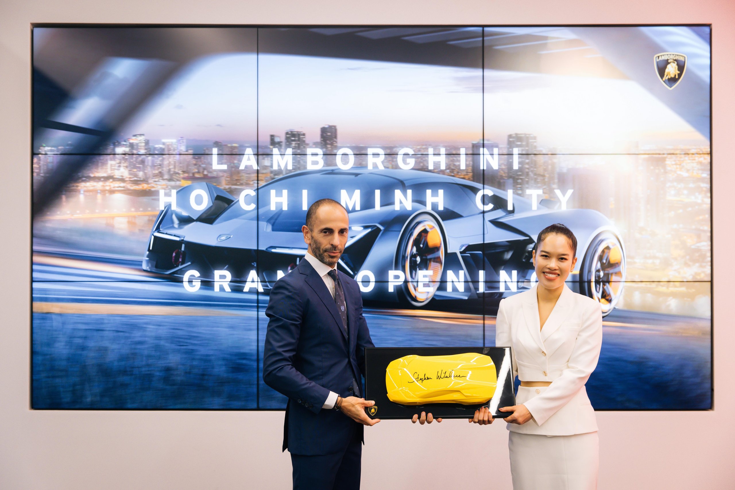 Lamborghini Plants Its Flag In Vietnam With A Ho Chi Minh City Showroom That Doubles As A 60Th Anniversary Statement 11 Two individuals pose with a commemorative plaque during the grand opening of the lamborghini ho chi minh city dealership