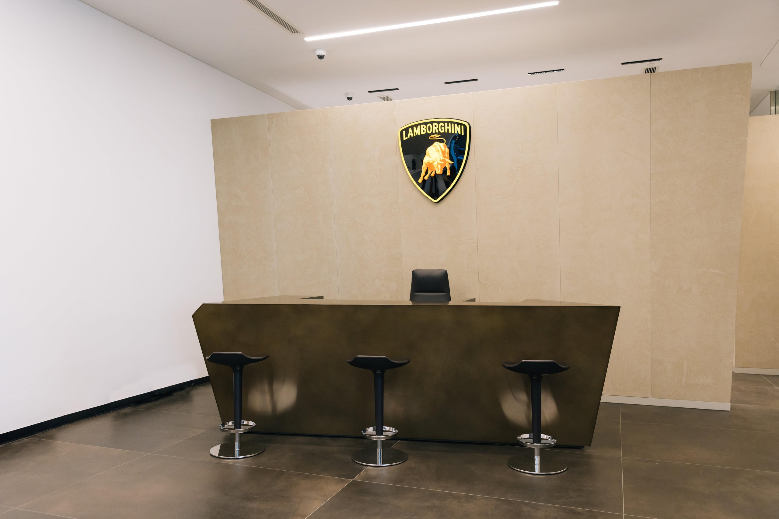 Lamborghini Plants Its Flag In Vietnam With A Ho Chi Minh City Showroom That Doubles As A 60Th Anniversary Statement 13 The reception area of the lamborghini ho chi minh city dealership featuring an angular desk and illuminated lamborghini shield logo on the wall