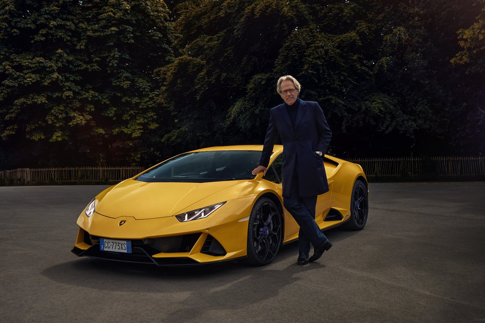 The Duke of Richmond leaning against a yellow Lamborghini Huracán Tecnica at Goodwood with trees in the background