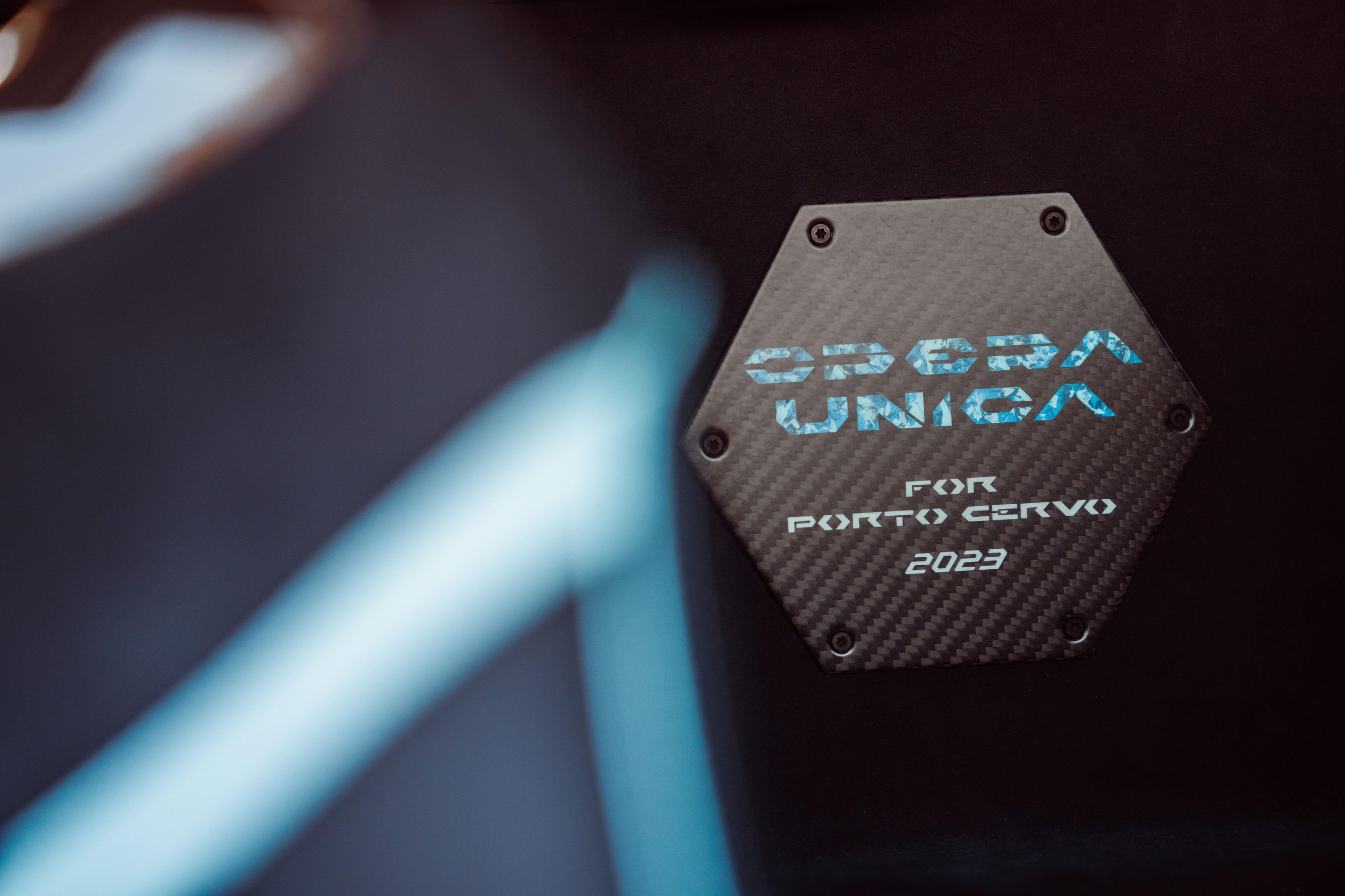 370 Hours Of Blue: How Lamborghini'S Opera Unica Sterrato Turns Paint Into Philosophy 11 Close-up of the hexagonal carbon fiber plaque reading 'opera unica for porto cervo 2023' inscribed in blue