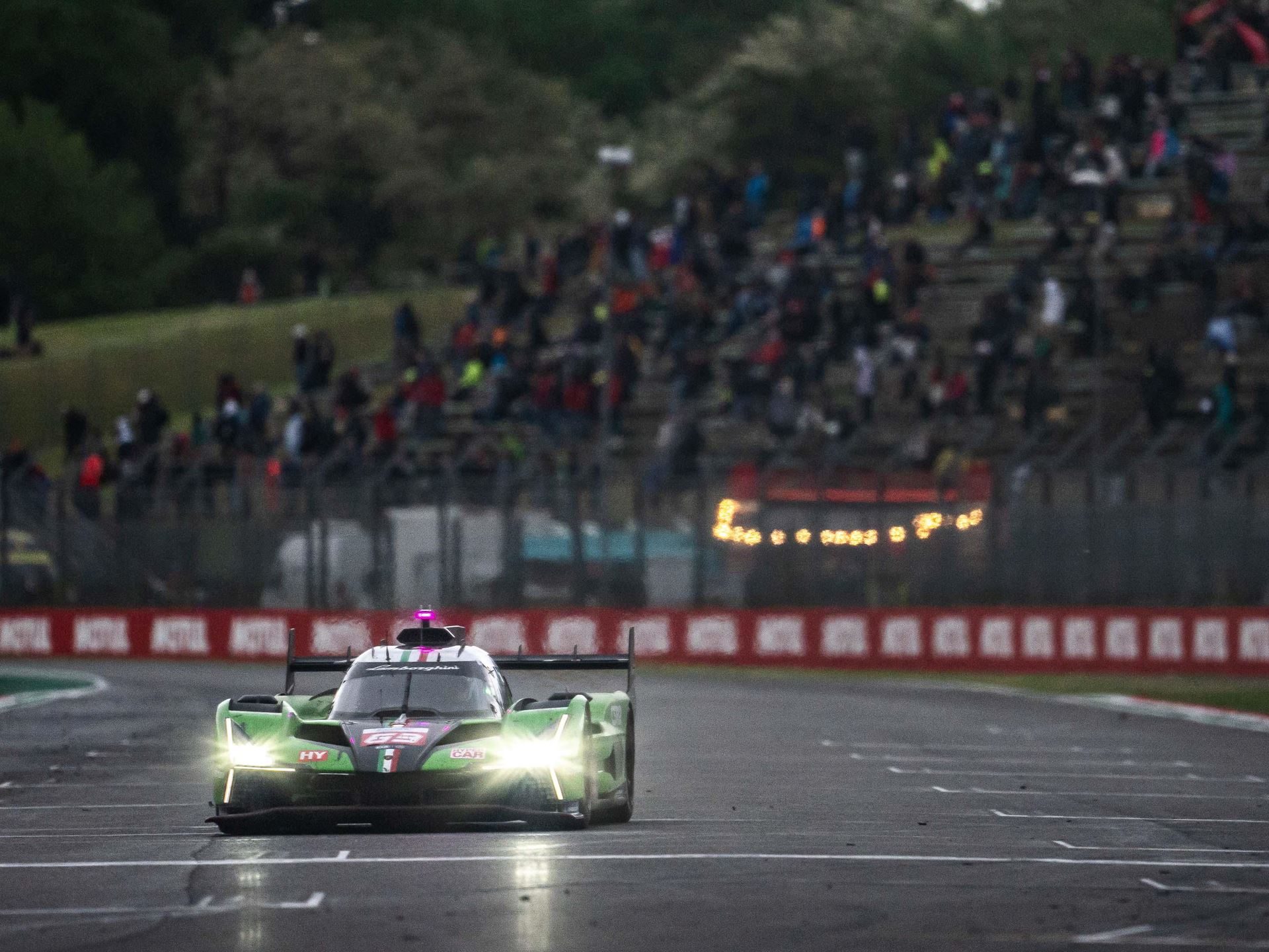 Lamborghini Sc63 Heads To Interlagos Carrying Le Mans Momentum Into Wec'S Second Half 9 Lamborghini sc63 hypercar approaching with headlights illuminated on track, spectators visible in the background