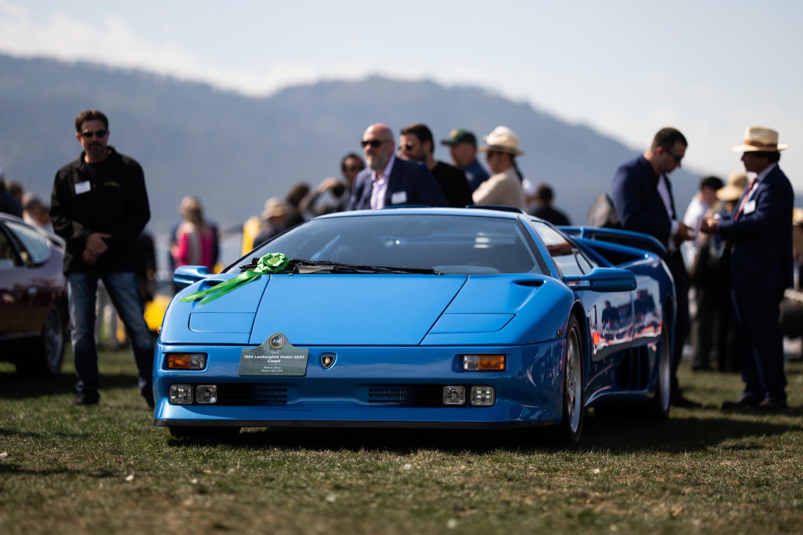Lamborghini Killed The All-Electric Lanzador, And Its Customers Barely Flinched 11 A vibrant blue lamborghini diablo se30 displayed on the grassy field at pebble beach, showing its classic wedge shape, pop-up headlights, and wide stance