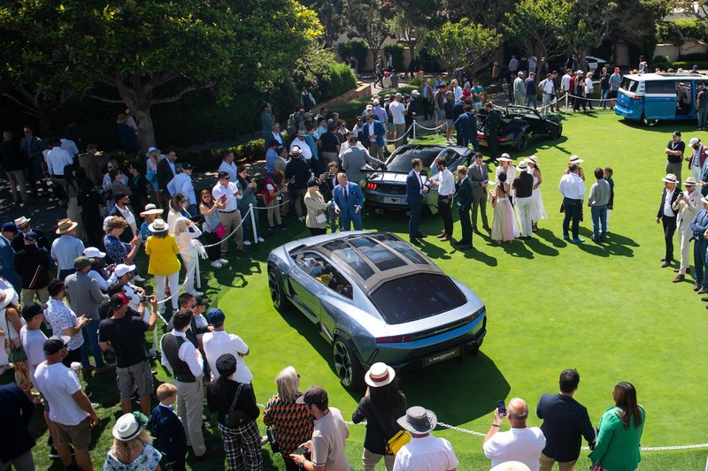 Elevated view of the Lamborghini Lanzador Concept on the Pebble Beach Concept Lawn surrounded by crowds of spectators, showing its futuristic SUV-coupe silhouette and panoramic glass roof
