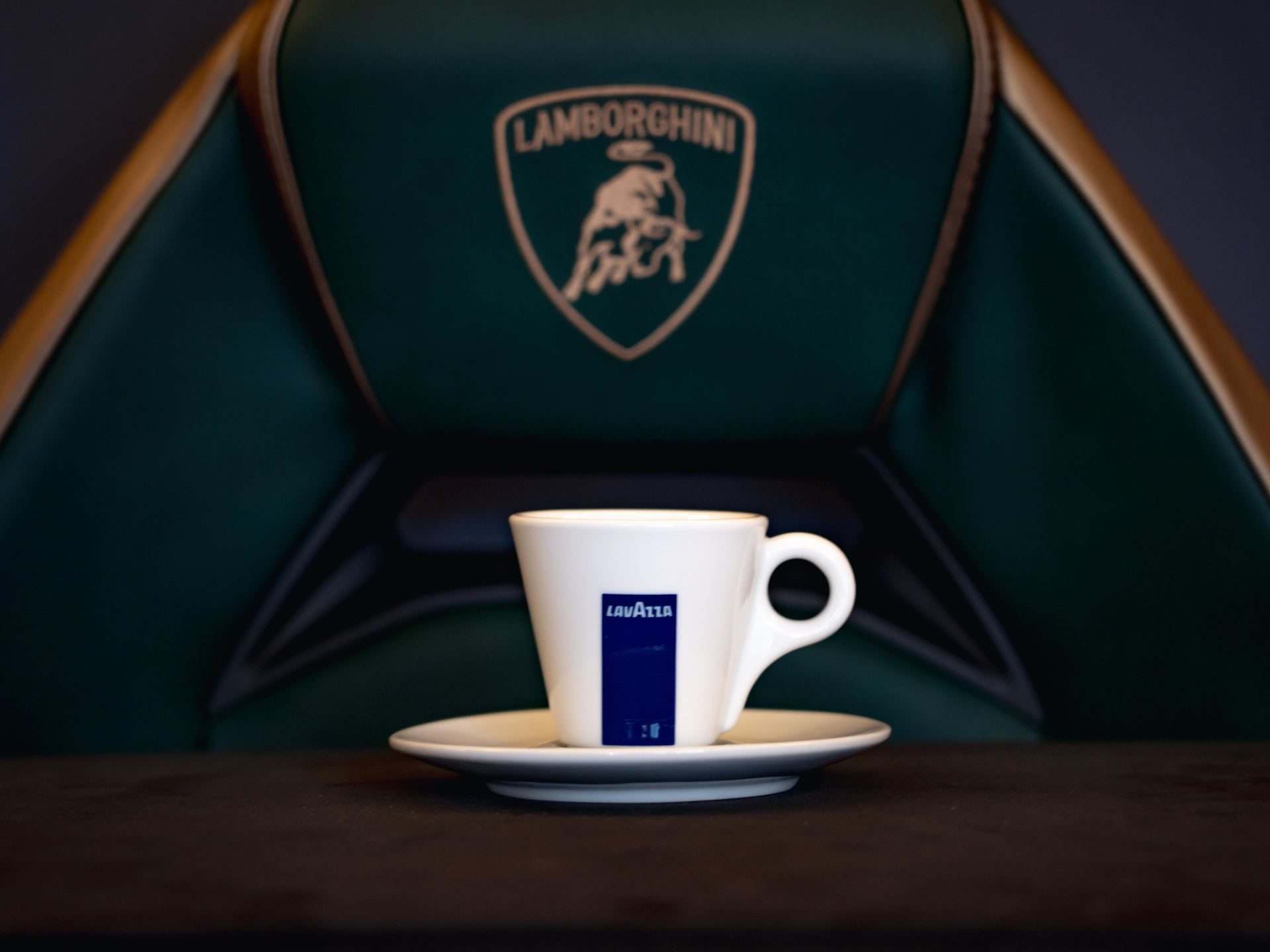 Lamborghini Partners With Lavazza To Pour Italian Luxury Beyond The Showroom 5 White lavazza espresso cup on a dark surface with a green lamborghini seat and gold logo visible in the background
