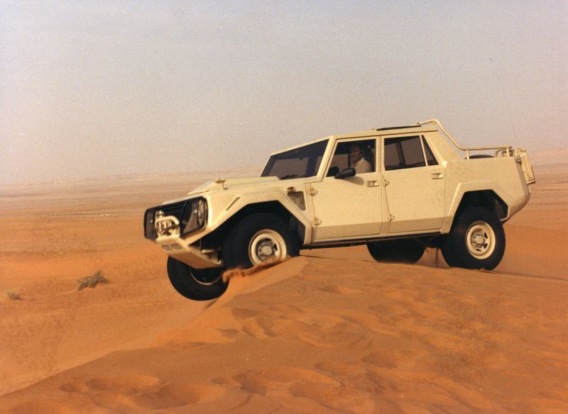 White Lamborghini LM002 mid-air over a sand dune in the desert