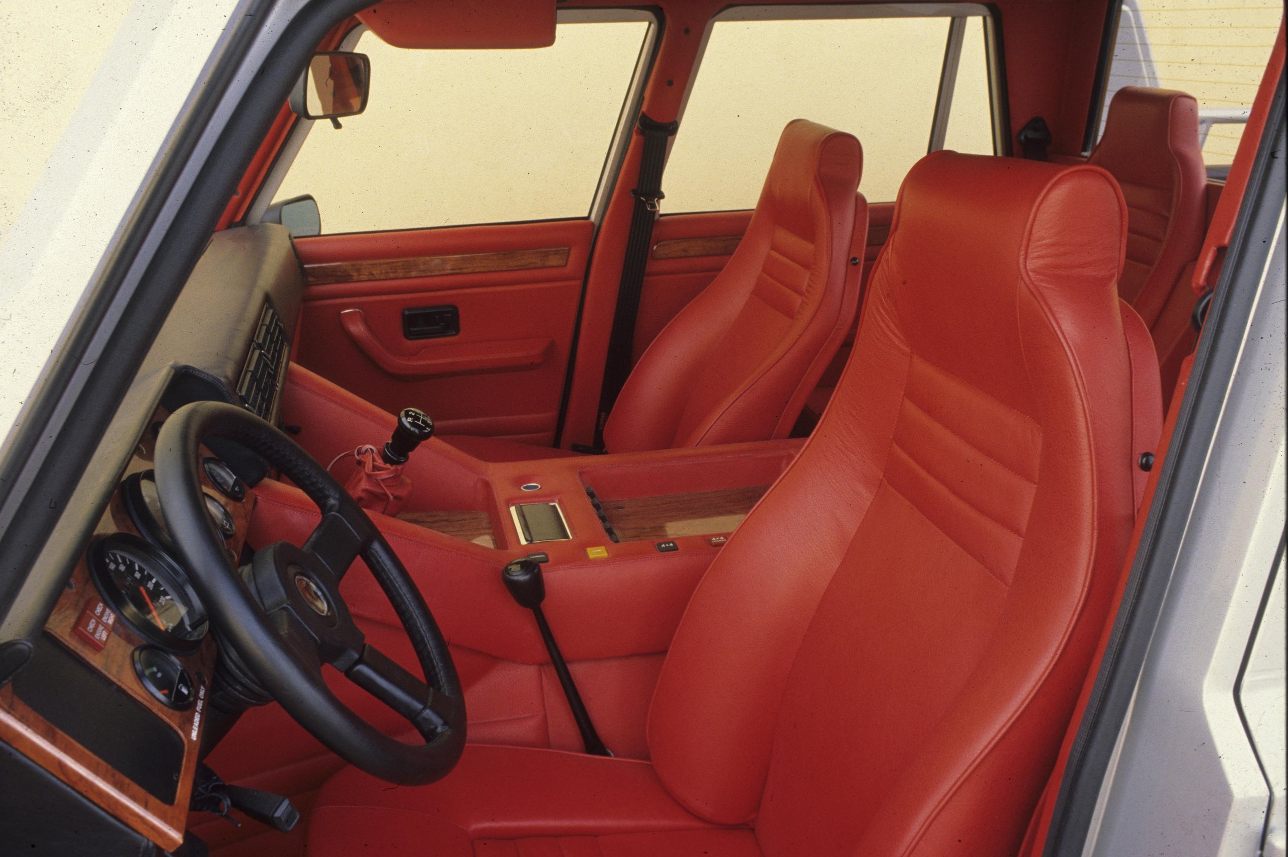 The 'Rambo Lambo' At 40: How Lamborghini'S V12 Off-Roader Invented The Super Suv And Paved The Road To The Urus 7 High-angle interior of lamborghini lm002 showing red leather seats, dashboard, and wooden trim