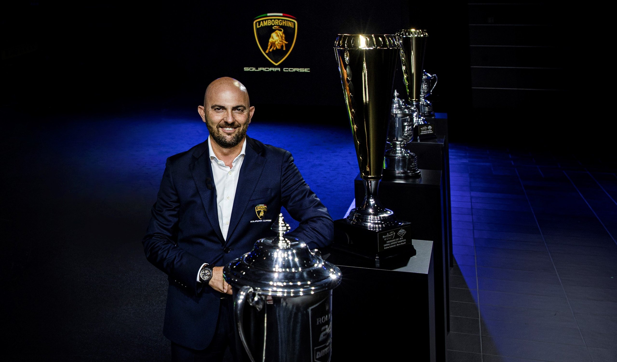 Lamborghini'S Lmdh Gambit: Why The Sc63 Program Is Really About The Road Cars You'Ll Buy Next 7 Lamborghini motorsport executive standing beside gleaming trophies with squadra corse branding in the background