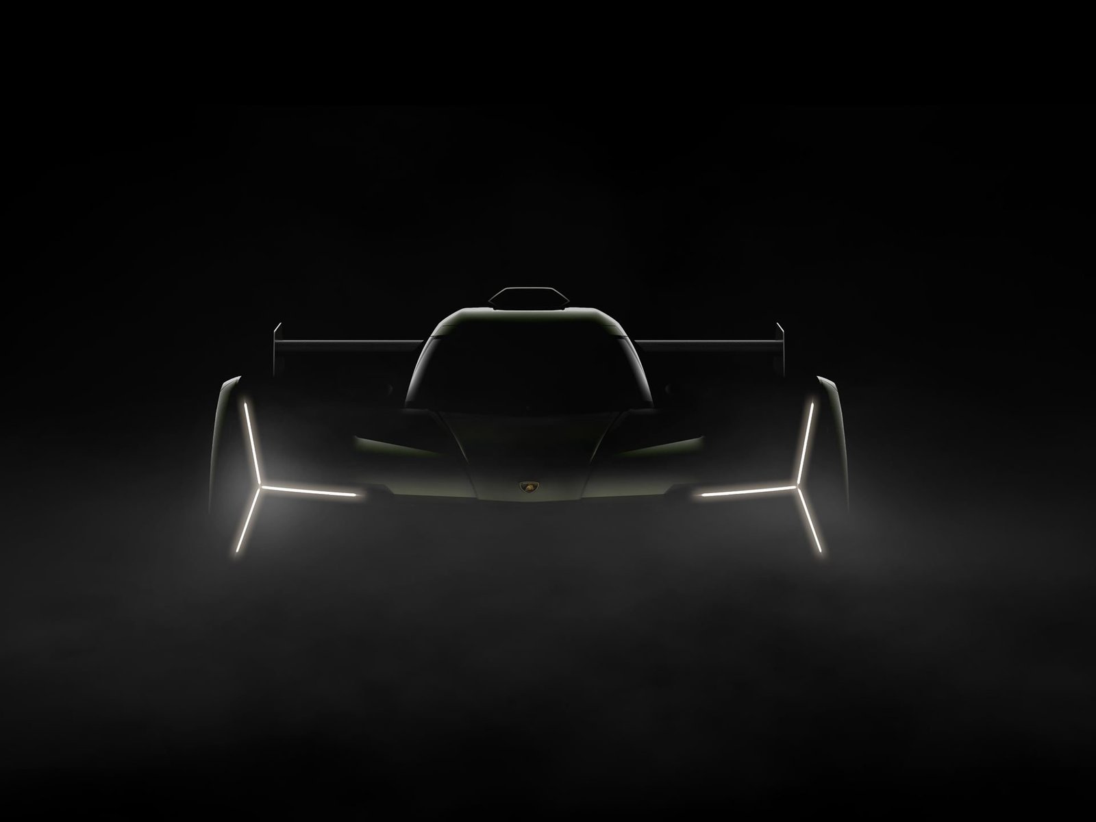 Lamborghini SC63 LMDh prototype in a dark studio, showing its Y-shaped LED headlights and low aerodynamic silhouette