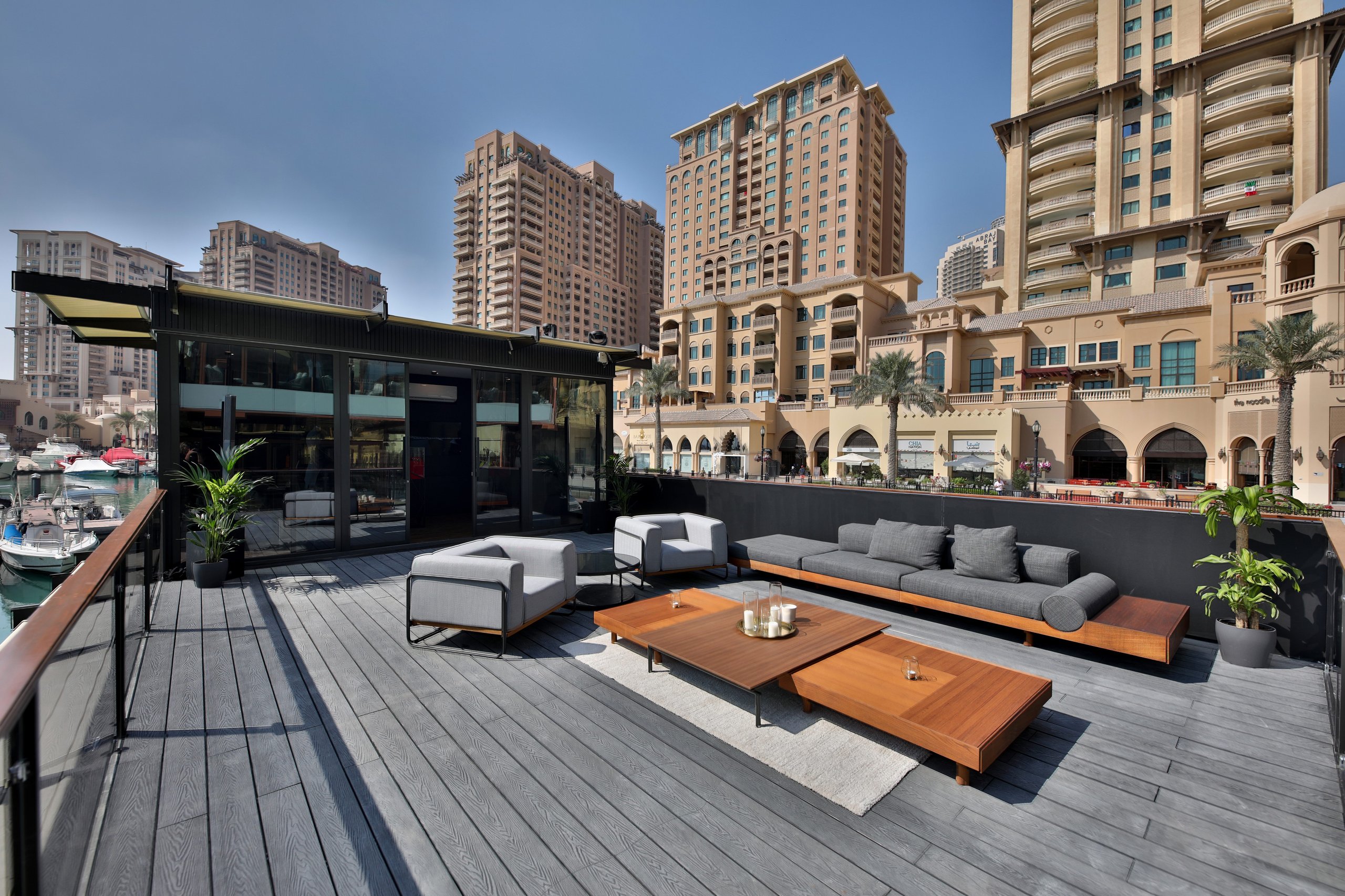 Expansive outdoor terrace of the lamborghini lounge doha with modern seating and lush greenery against a backdrop of high-rise buildings and the marina