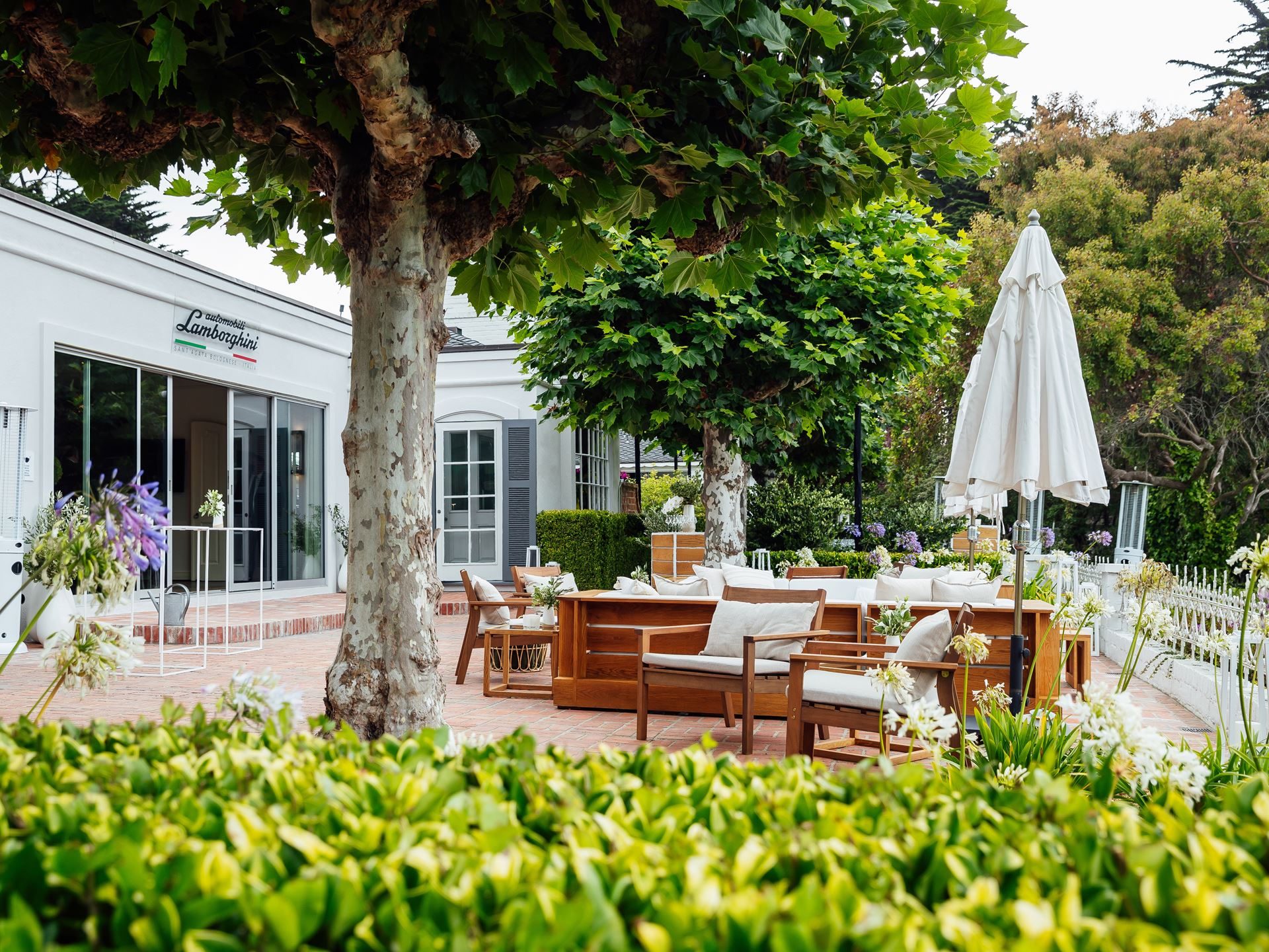 Inside Lamborghini'S Pebble Beach Playbook: How The Lounge Monterey Sells A Lifestyle, Not Just Supercars 3 Entrance to the lamborghini private lounge at pebble beach, with the brand logo on a white building surrounded by greenery and outdoor seating