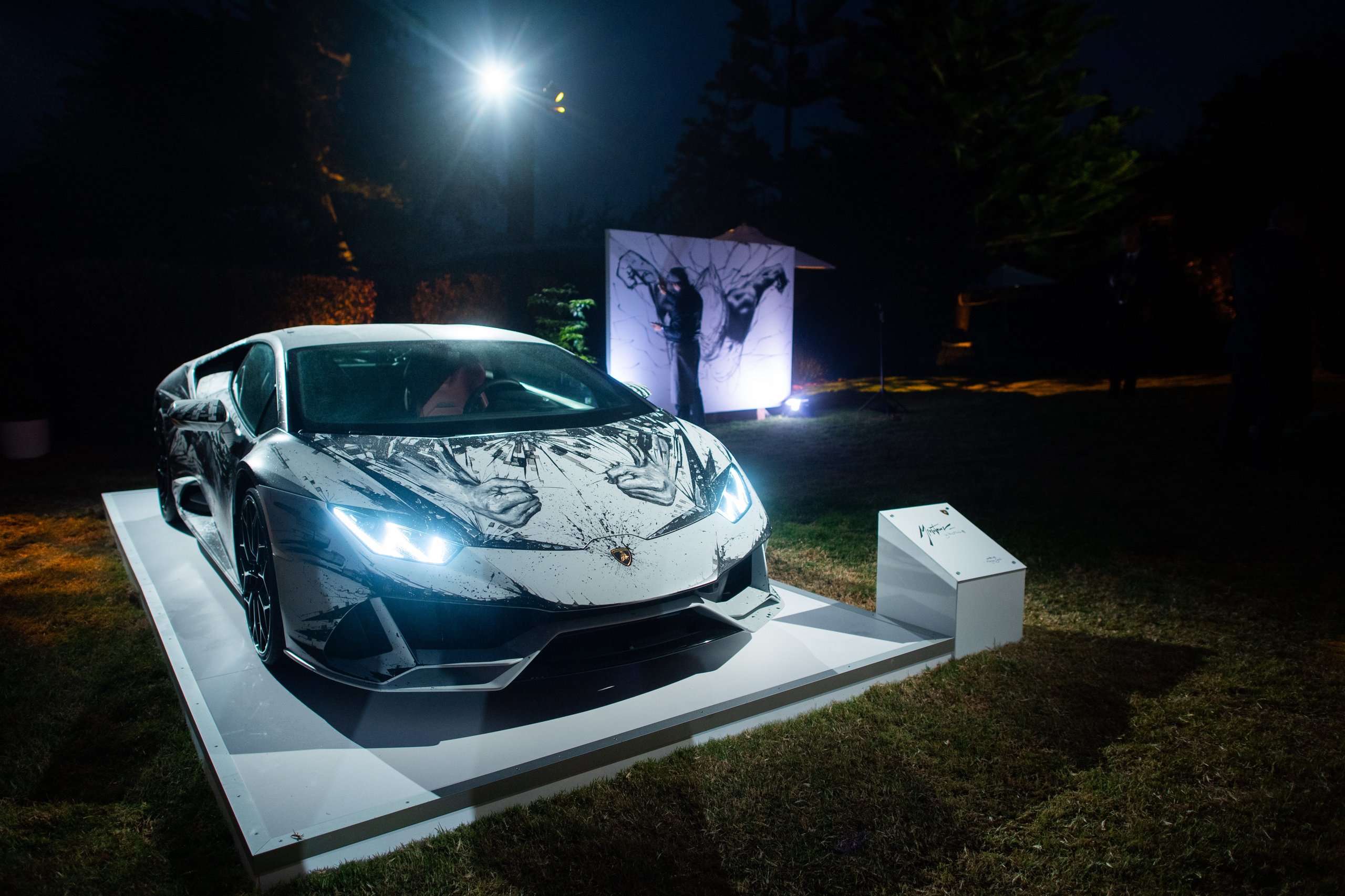 Inside Lamborghini'S Lounge Monterey: Where The Urus Performante Debut Became A Masterclass In Selling A Lifestyle 9 Lamborghini huracán sto with unique graphic wrap displayed at night with artist painting in the background at the lounge monterey