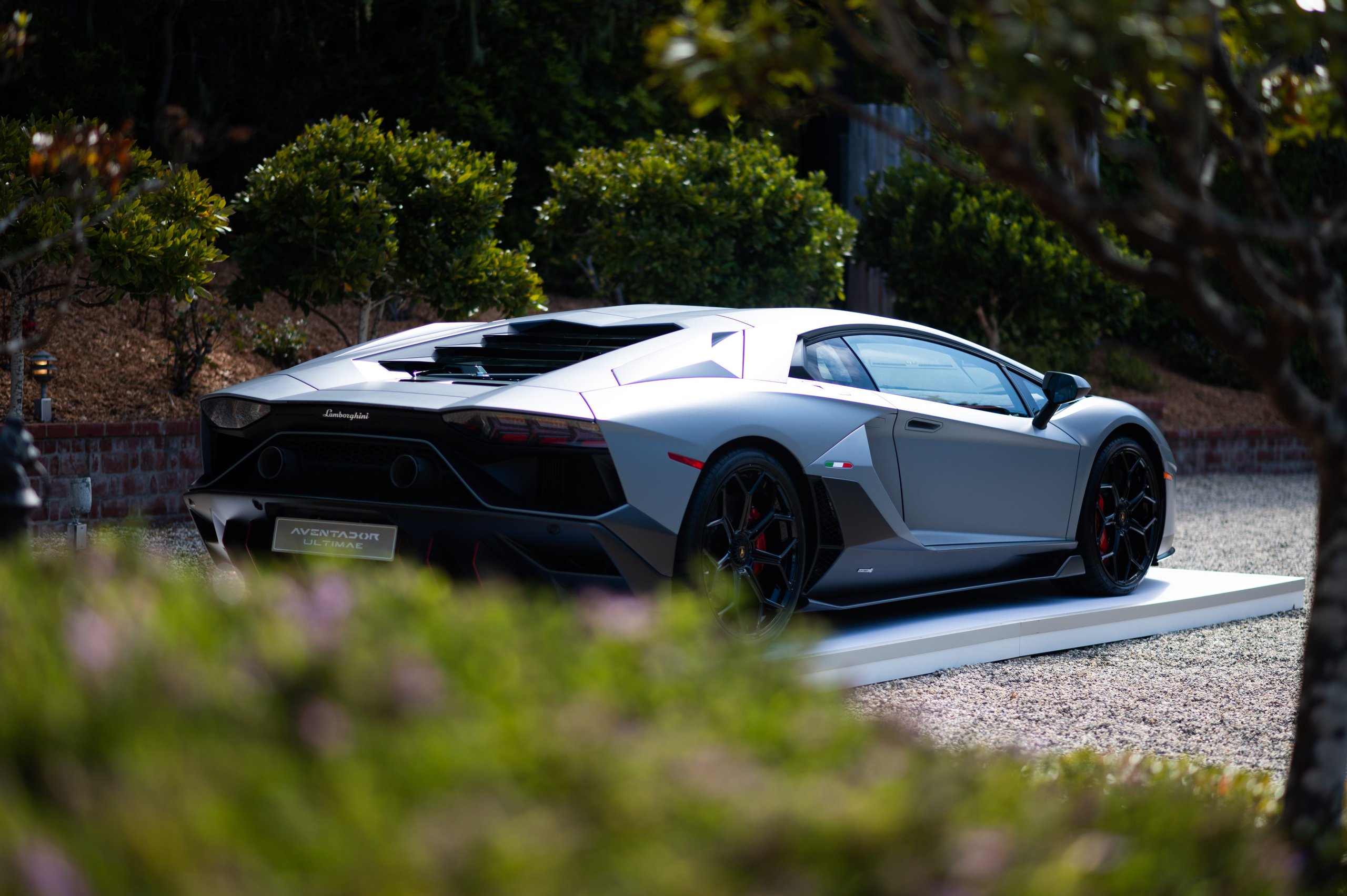 Inside Lamborghini'S Lounge Monterey: Where The Urus Performante Debut Became A Masterclass In Selling A Lifestyle 11 Grey lamborghini aventador lp 780-4 ultimae displayed on a white platform with lush greenery at the lounge monterey