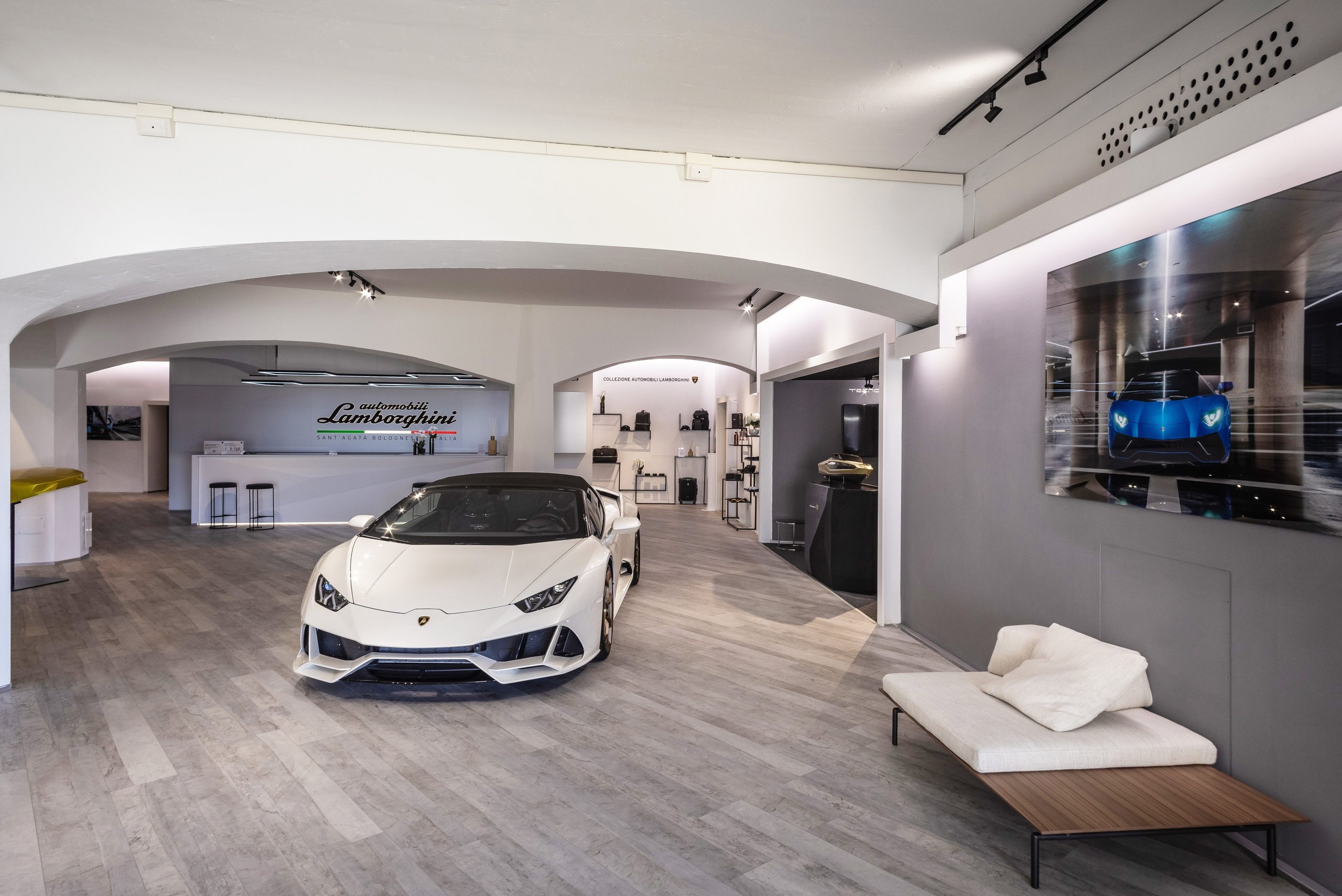 Porto Cervo'S Lamborghini Lounge: Where Ad Personam Meets The Sardinian Coast 3 White lamborghini huracán evo spyder displayed in the porto cervo lamborghini lounge showroom with lamborghini logo on the back wall
