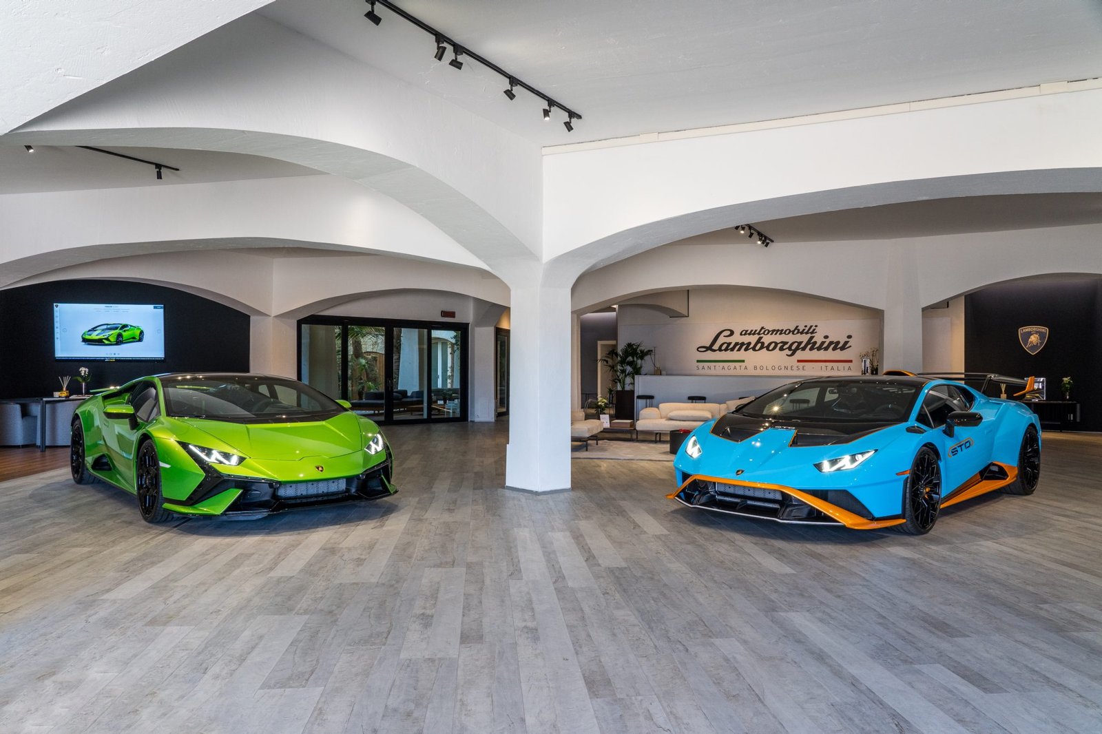 Green Lamborghini Huracán Tecnica and blue Huracán STO displayed inside the Lamborghini Lounge Porto Cervo showroom