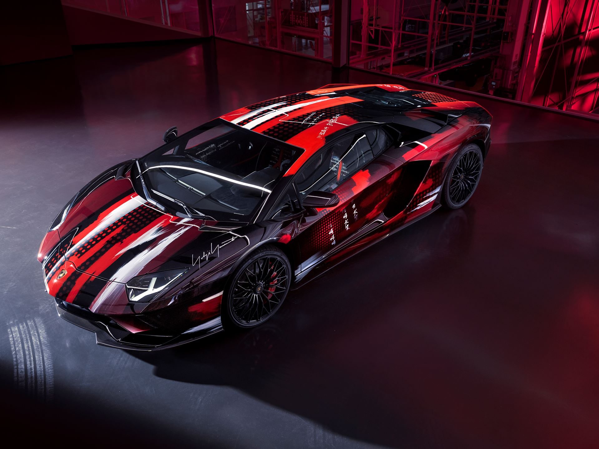Overhead view of the yohji yamamoto aventador s showing the black, red, and white abstract livery and japanese lettering on the bodywork