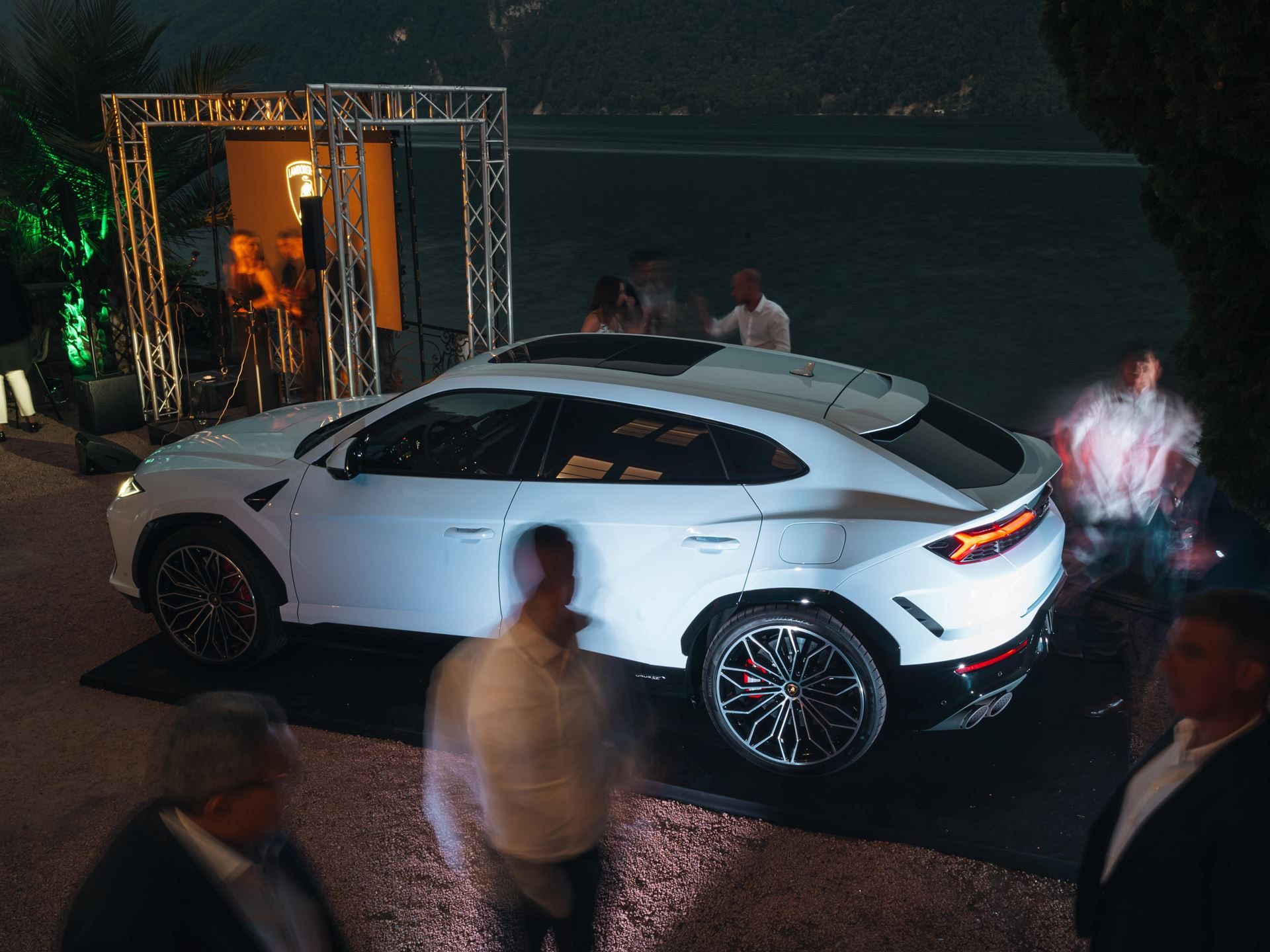 Lamborghini Lugano Turned Its First Birthday Into A Lakeside Stage For The Urus Se'S Swiss Debut 5 White lamborghini urus se displayed outdoors at an evening event with blurred guests, lake, and mountains in the background