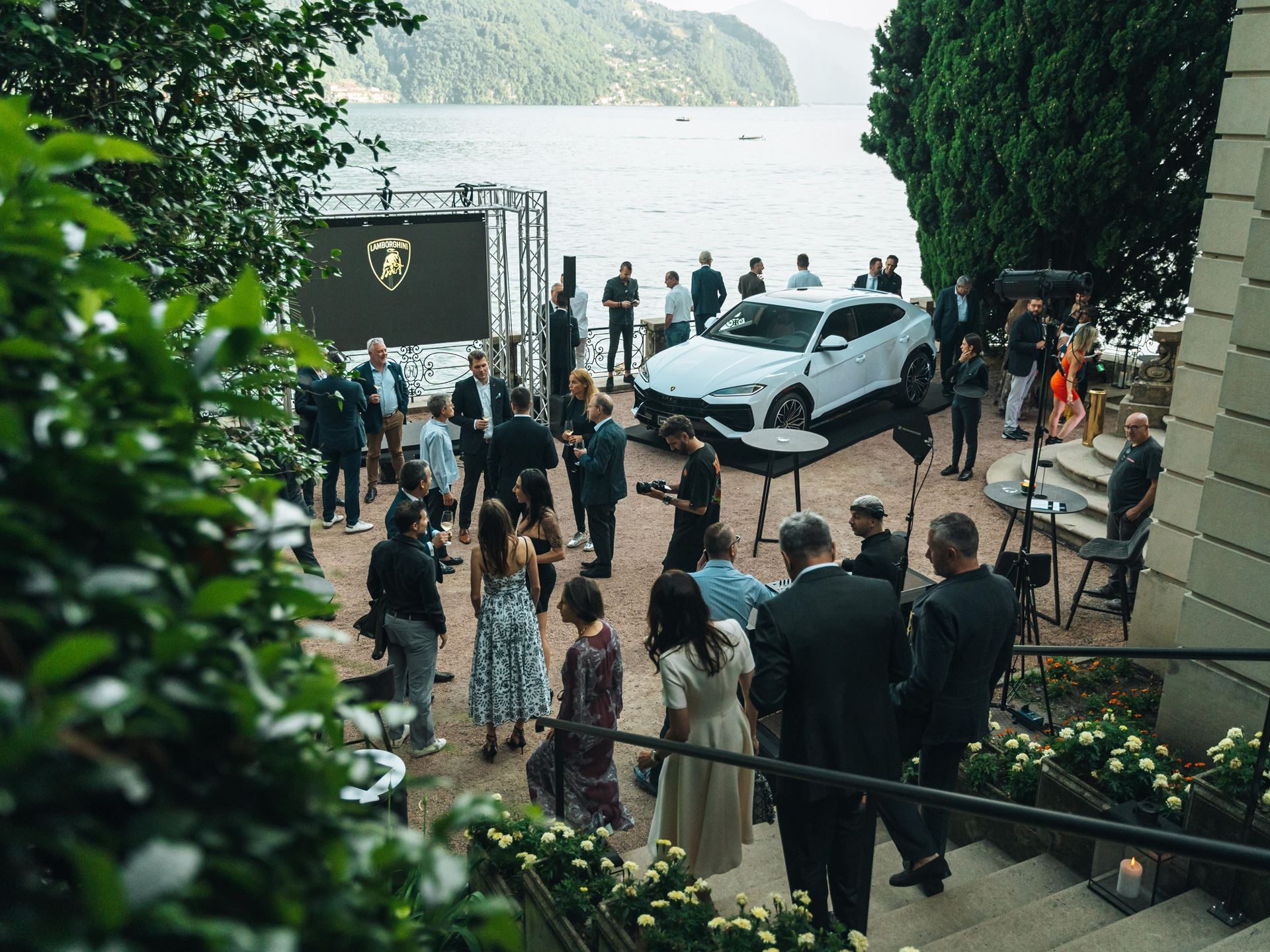 Lamborghini Lugano Turned Its First Birthday Into A Lakeside Stage For The Urus Se'S Swiss Debut 11 White lamborghini urus se displayed by the lake at an outdoor event with vip attendees gathered around