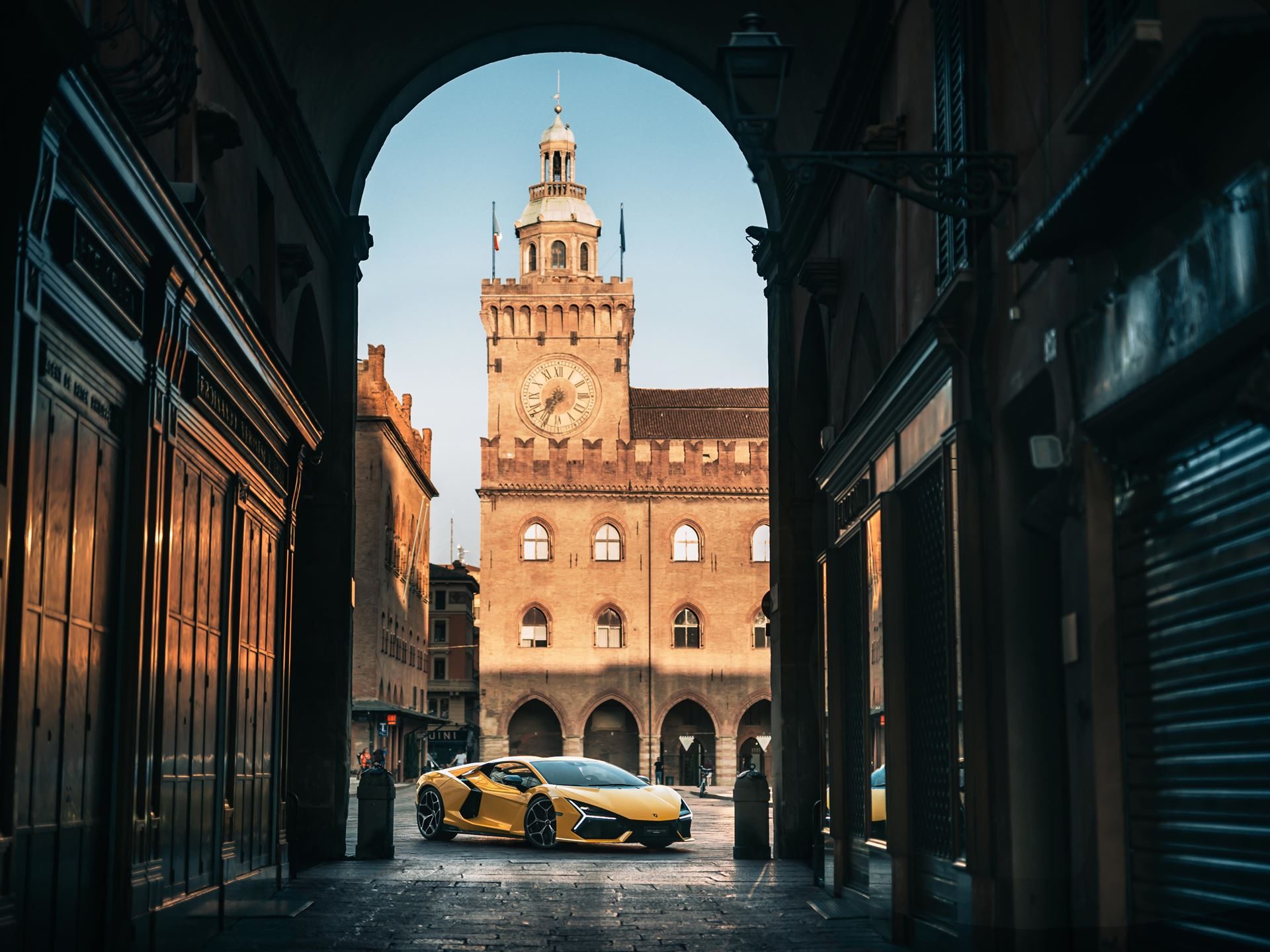 Why Lamborghini'S 'Made In Italy' Day Matters More Than National Pride 7 Yellow lamborghini revuelto parked under a historic archway with a grand clock tower visible in the background