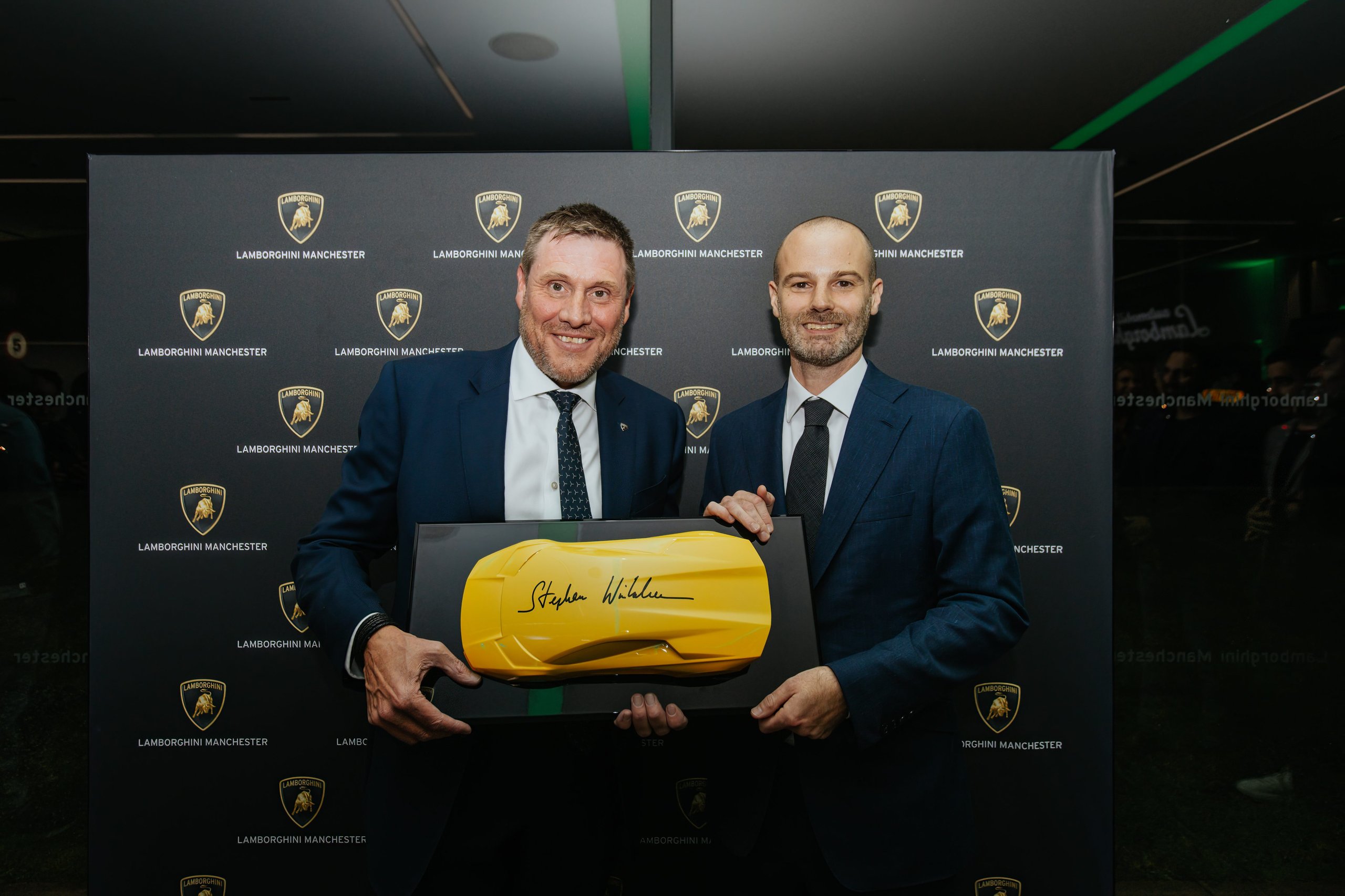 Lamborghini Manchester'S New Stockport Showroom Signals Where The Brand Is Placing Its Uk Bets 3 Two executives holding a signed yellow lamborghini scale model at the lamborghini manchester showroom opening event