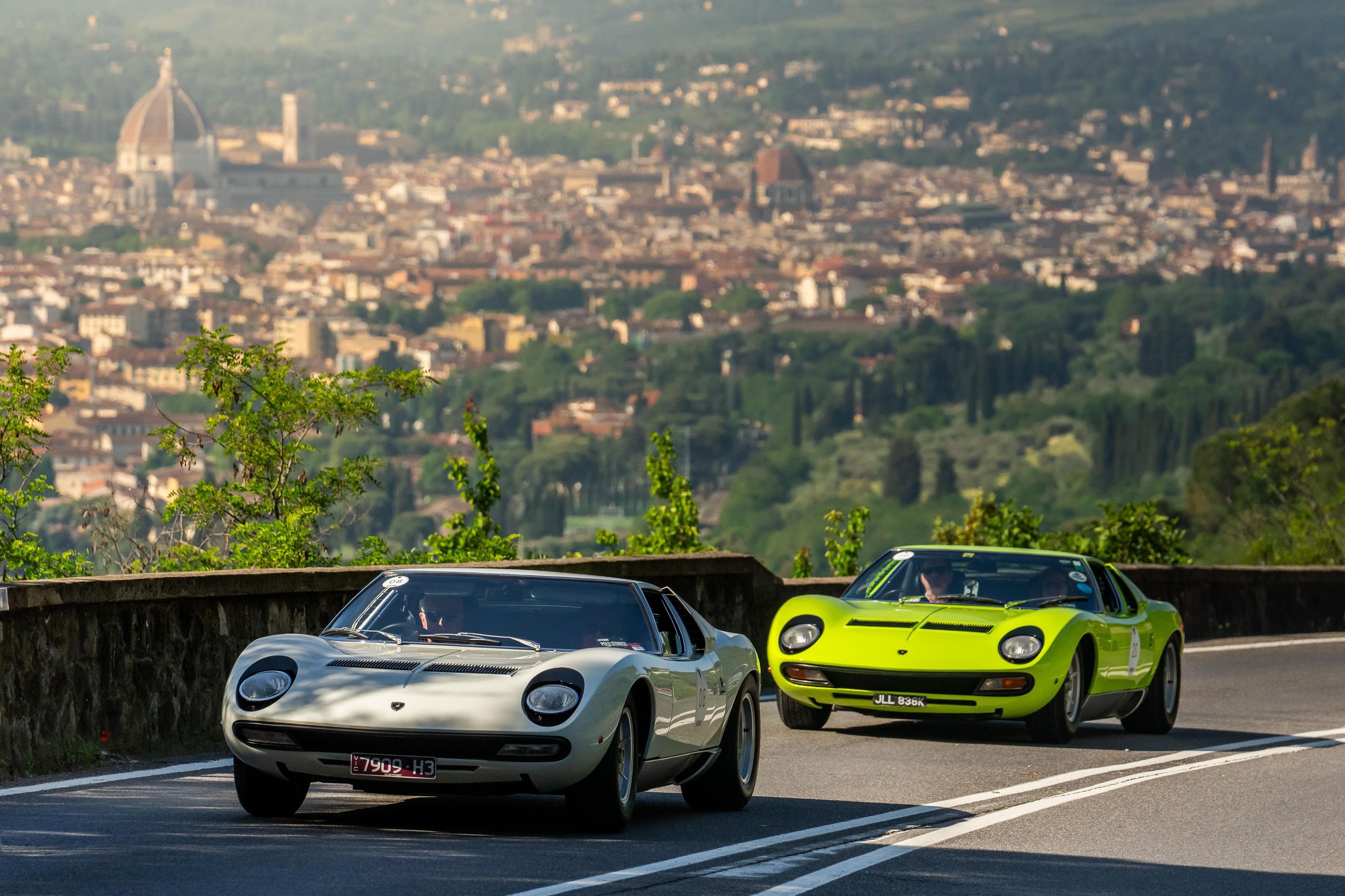 Twenty Miuras, 500 Kilometers, And One Fenomeno Roadster: Inside Lamborghini'S 2026 Polo Storico Giro 5 Two classic lamborghini miuras, one white and one lime green, driving on a winding mountain road overlooking the florence skyline with its prominent dome