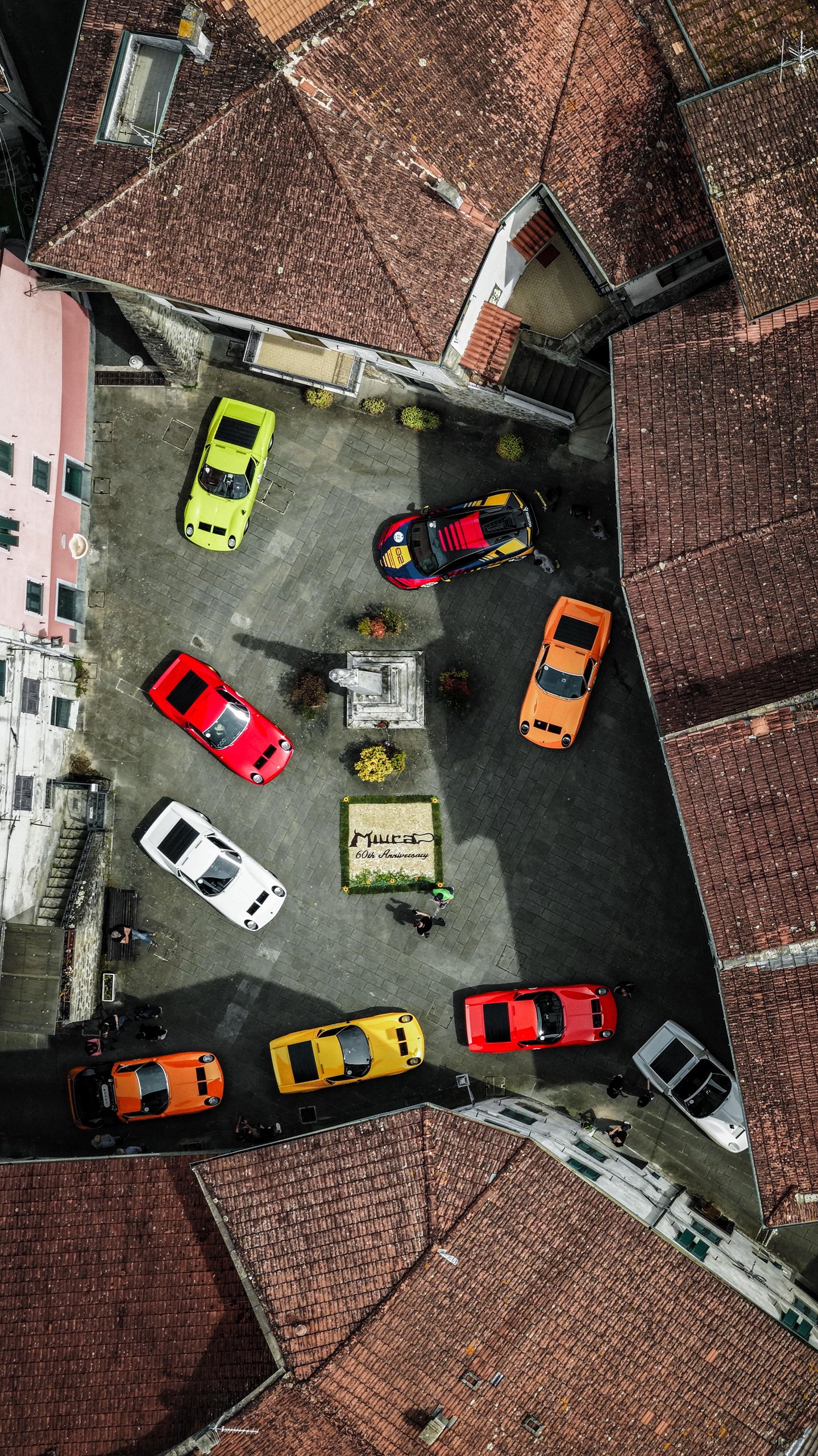 Twenty Miuras, 500 Kilometers, And One Fenomeno Roadster: Inside Lamborghini'S 2026 Polo Storico Giro 3 Aerial view of a town square filled with lamborghini miuras of various colors parked around a central miura 60th anniversary display