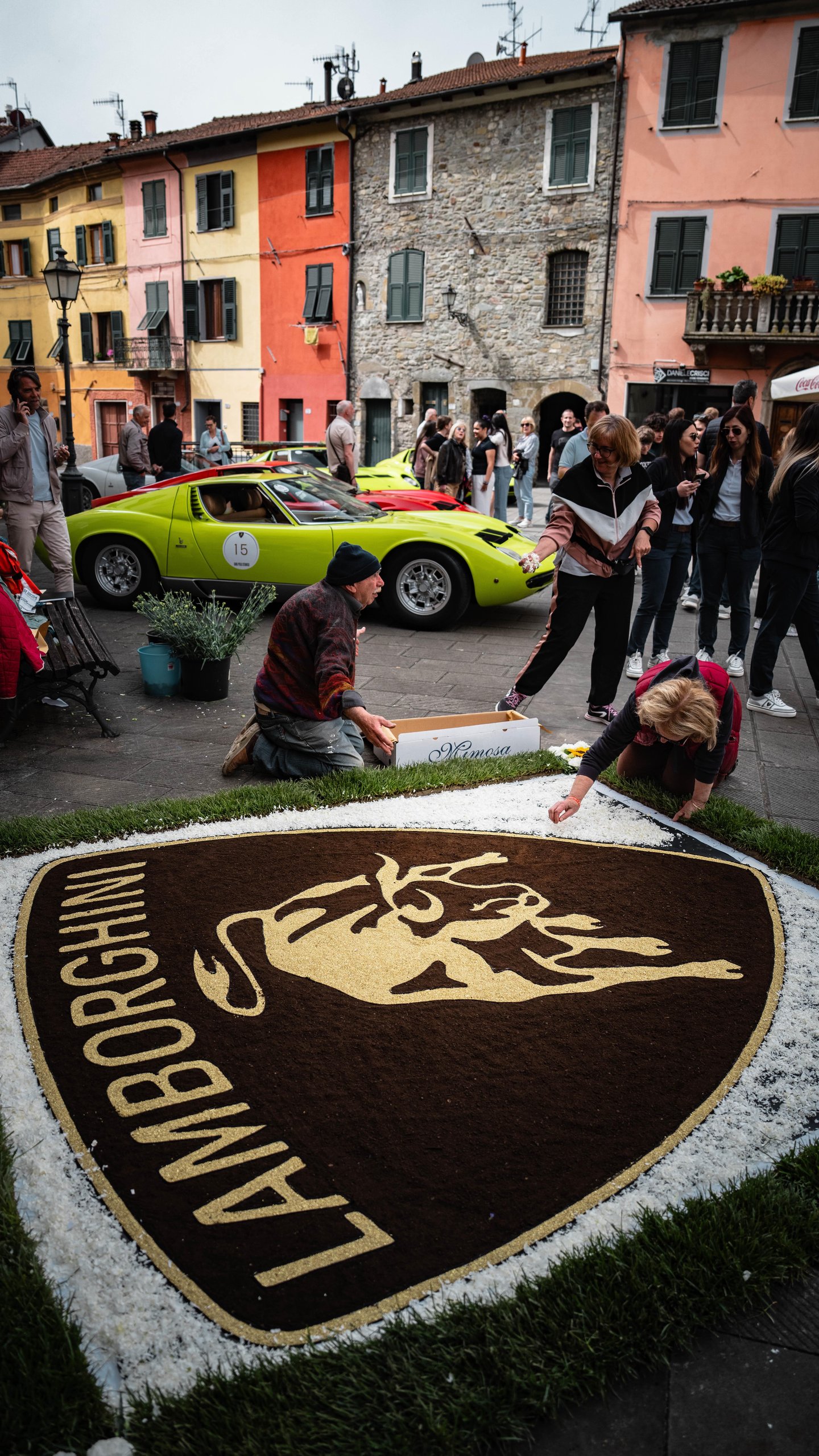 Twenty Miuras, 500 Kilometers, And One Fenomeno Roadster: Inside Lamborghini'S 2026 Polo Storico Giro 7 A lime green lamborghini miura parked in a bustling town square where people create a large floral lamborghini logo on the ground