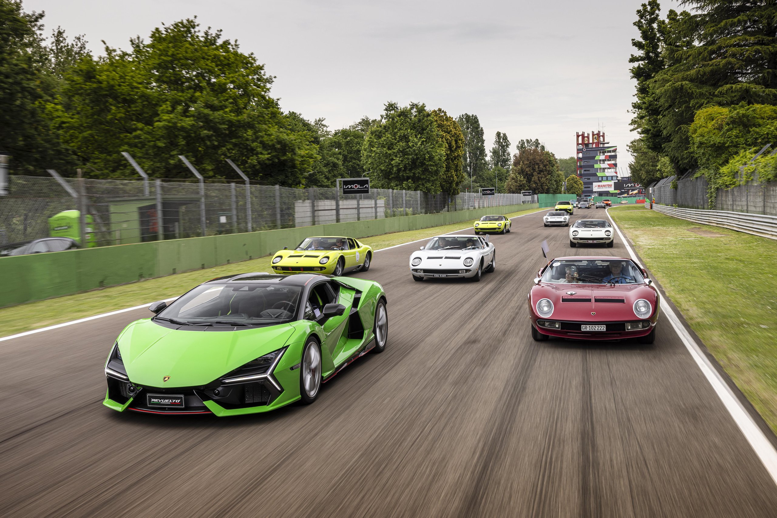 Twenty Miuras, 500 Kilometers, And One Fenomeno Roadster: Inside Lamborghini'S 2026 Polo Storico Giro 11 A modern green lamborghini revuelto leads a convoy of classic lamborghini miuras in various colors on a race track at imola