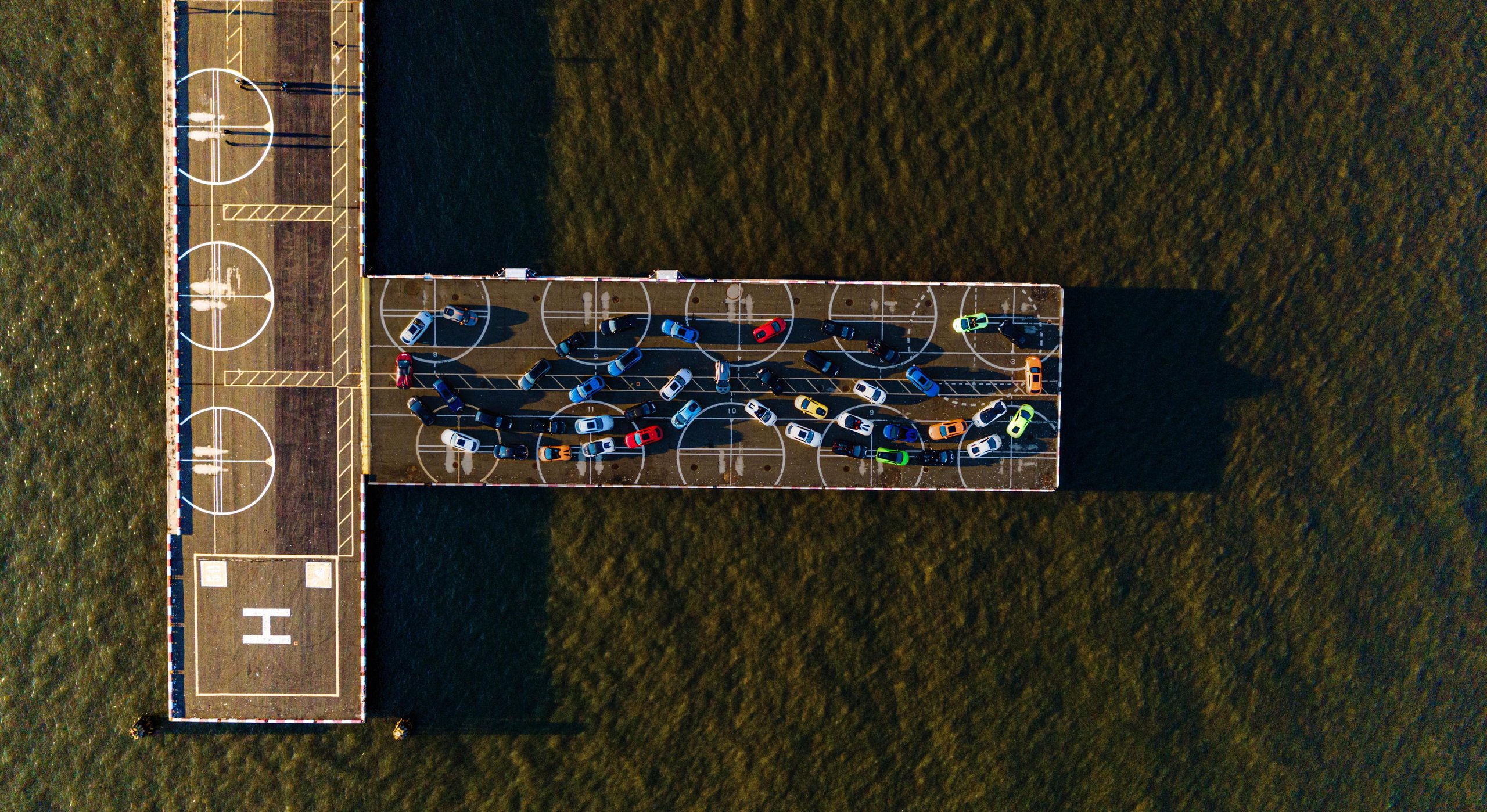 Over 800 Lamborghinis Wear Mustaches For Movember, And Bologna Fc Joins The Parade 3 Aerial view of numerous colorful lamborghini huracáns arranged in a mustache formation on a waterfront pier
