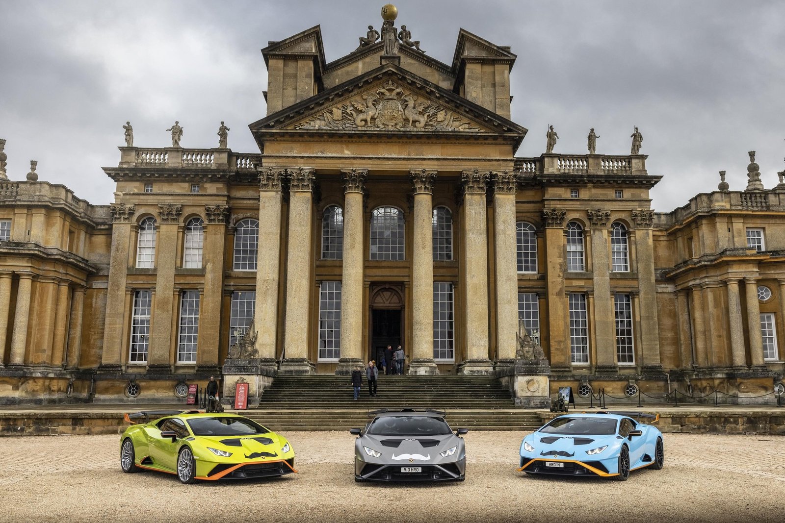 Three Lamborghini Huracáns with Movember mustache decals parked in front of a grand classical building